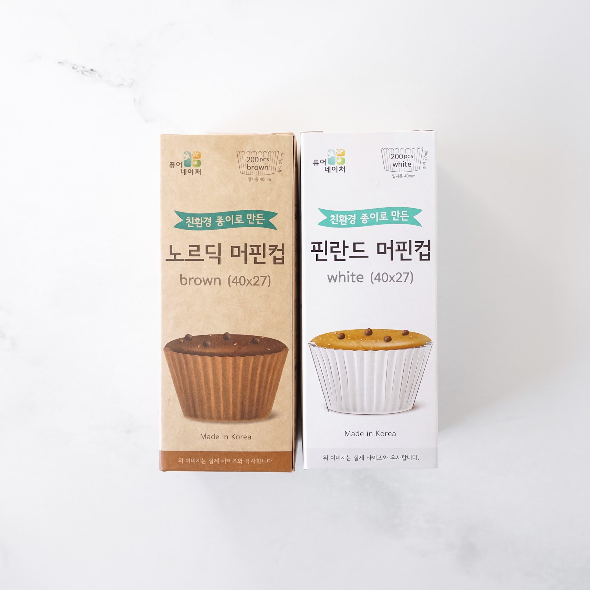 Two boxes of muffin cups, one brown and one white, on a white background.