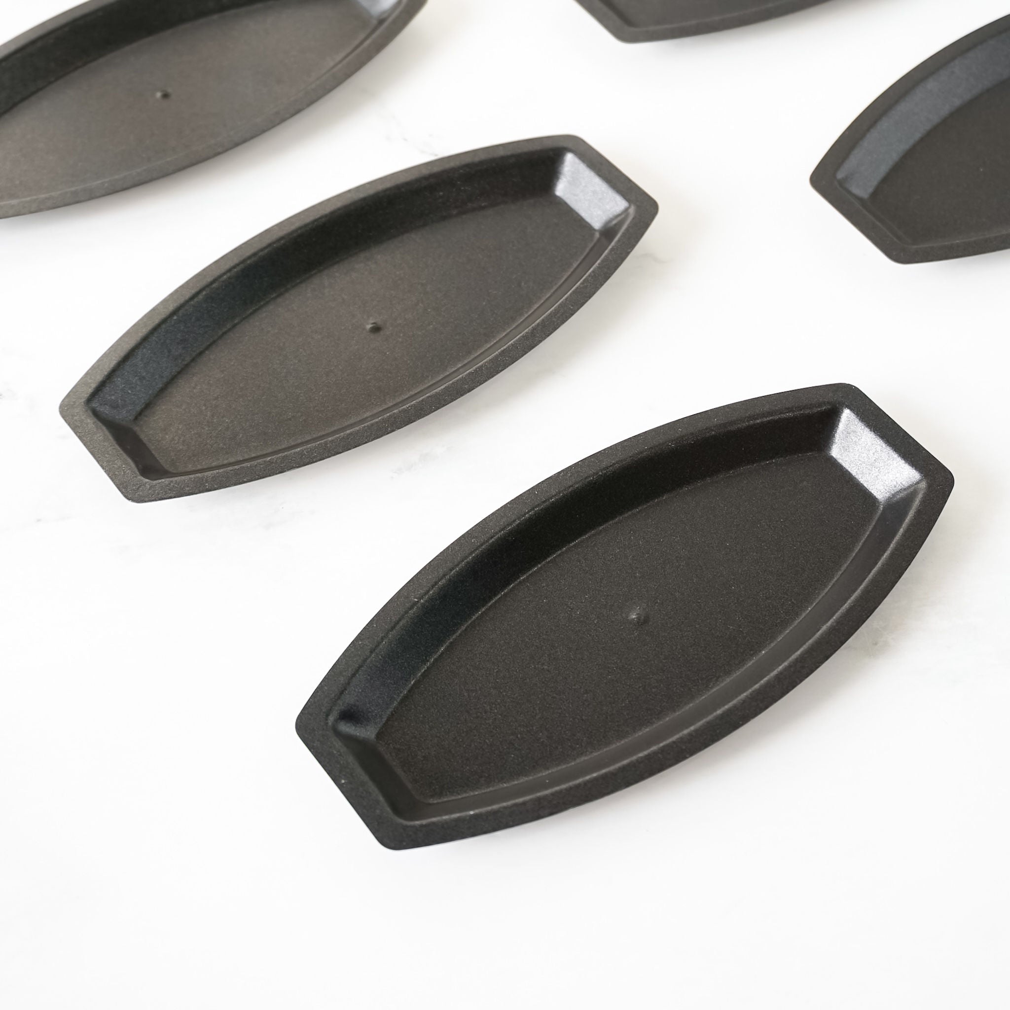 Set of black metal boat-shaped baking pans on a white background