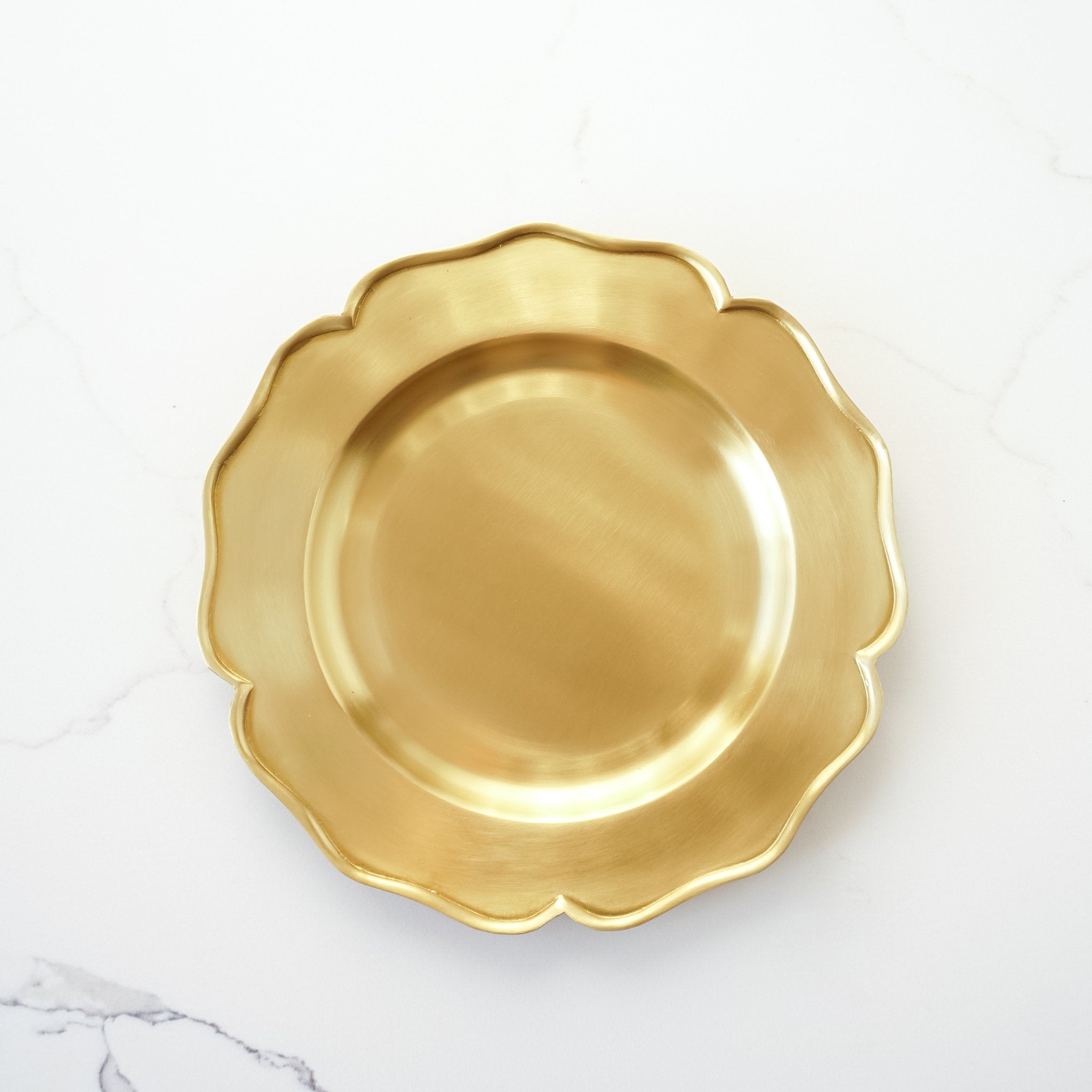 An antiqued brass trays with ruffled edges on a white background.