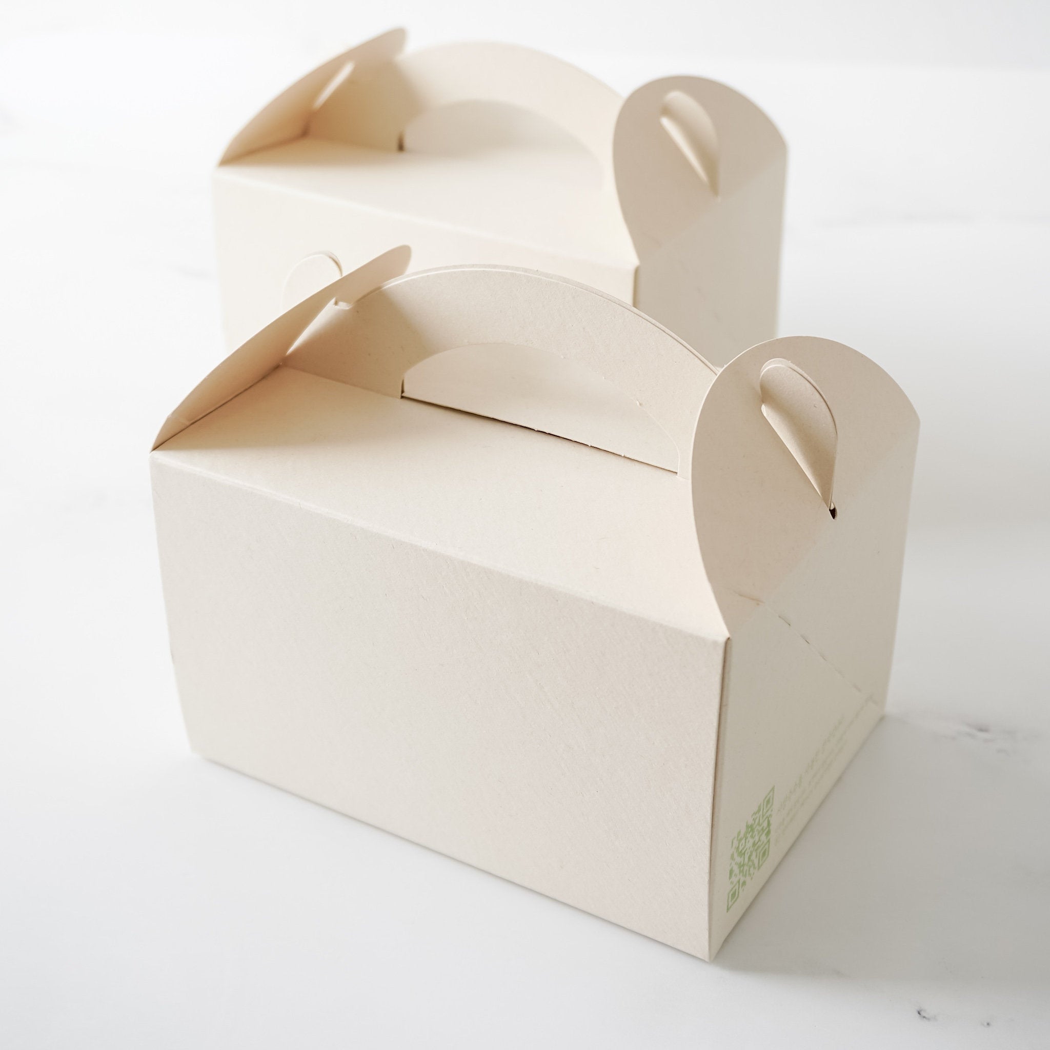 Two light beige natural boxes with cut-out handles. The boxes are empty and are sitting on a white surface.