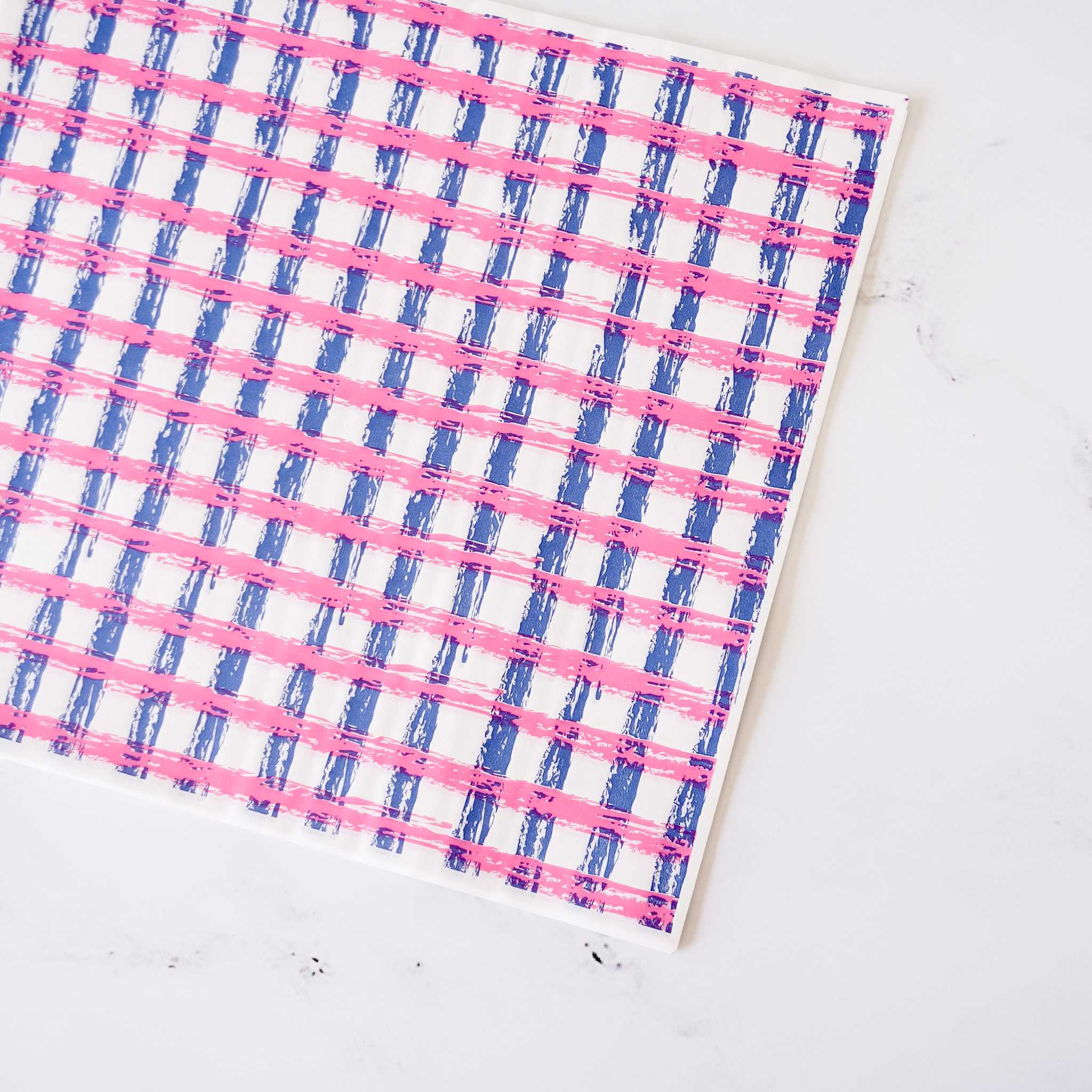 A white background with a pink and blue gingham pattern. The pattern is made of thick, brushstroke-like lines.