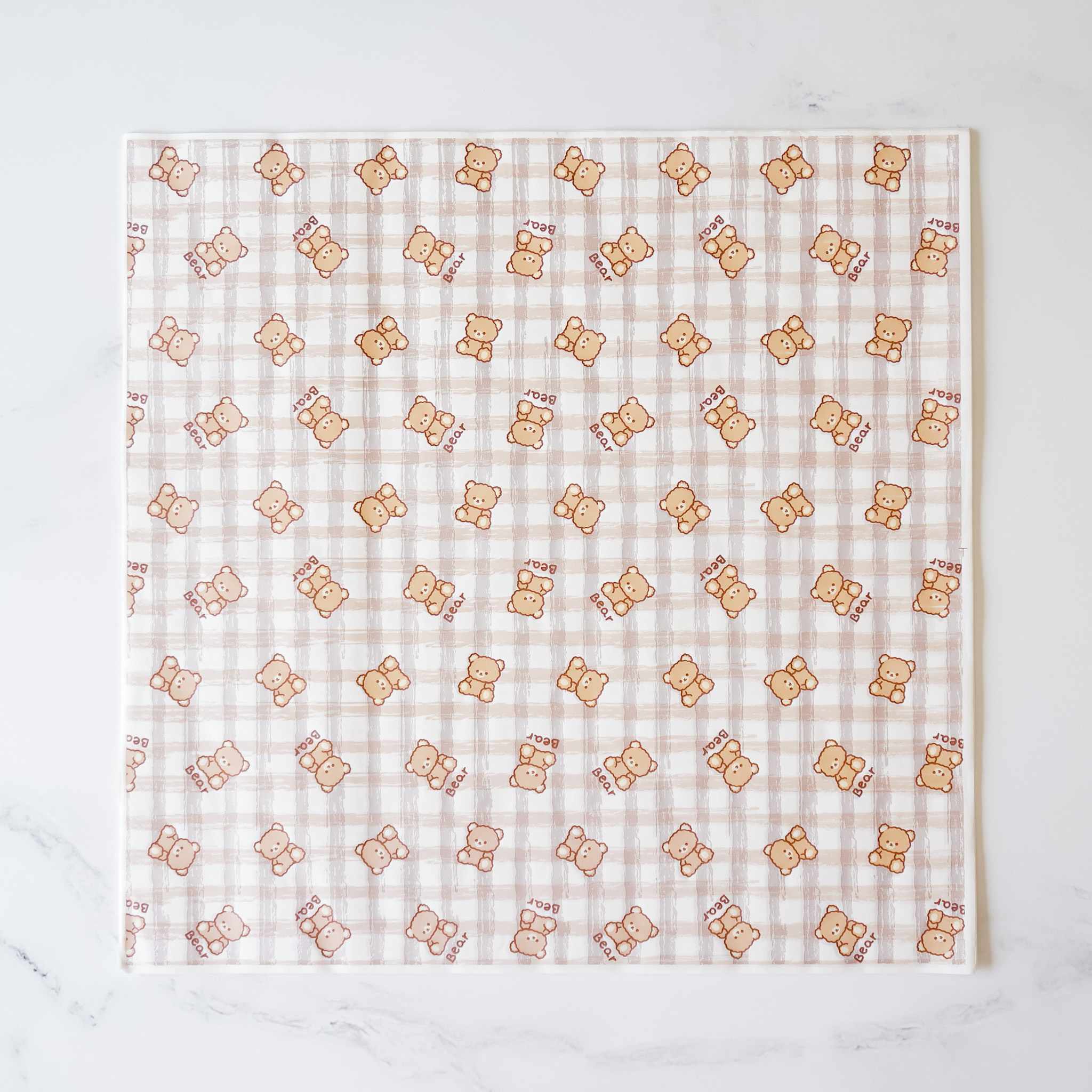 A white and brown checkered pattern with a repeating image of a brown bear. The bear is wearing a red bow tie and has the word &