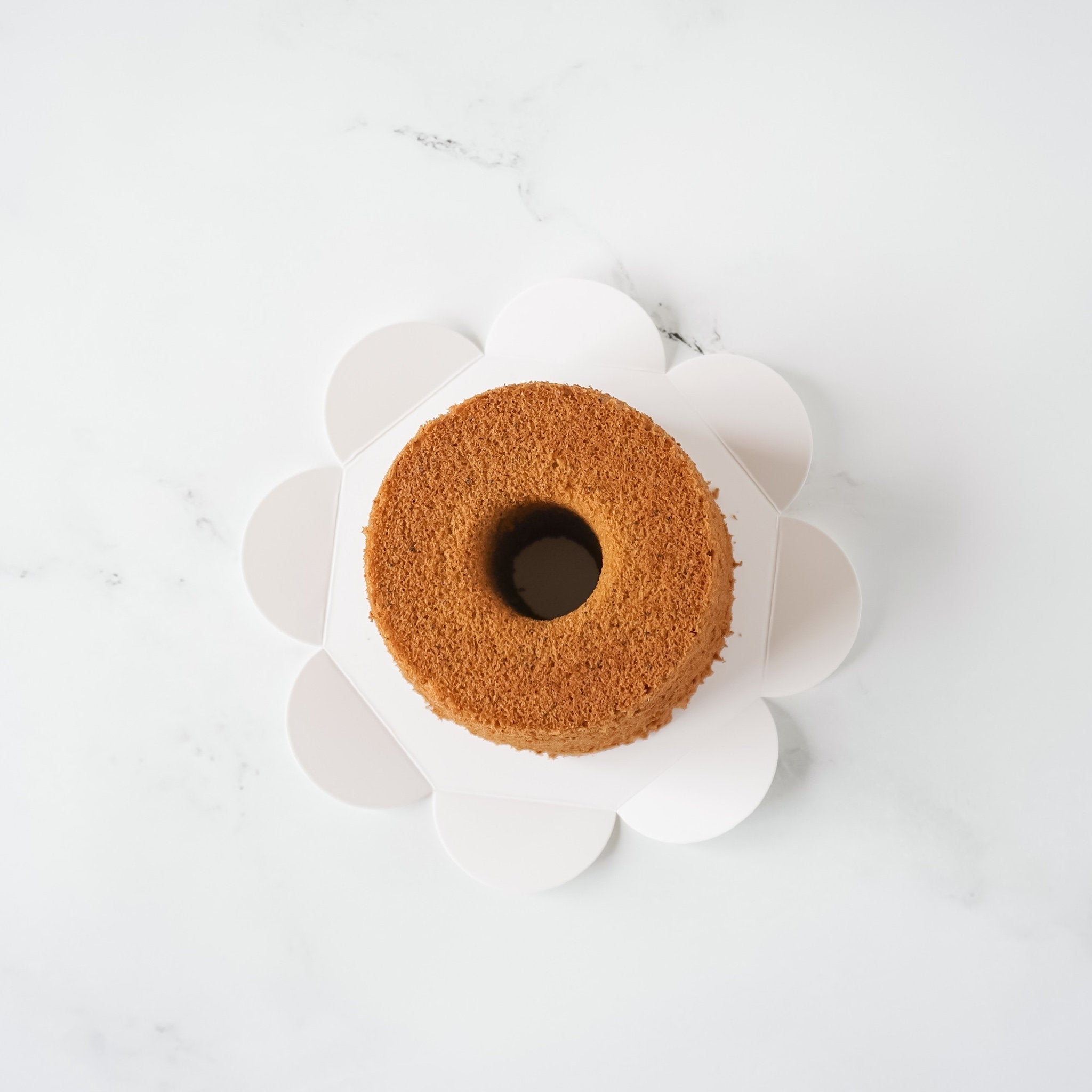 A chiffon cake on a flower-shaped cake board.