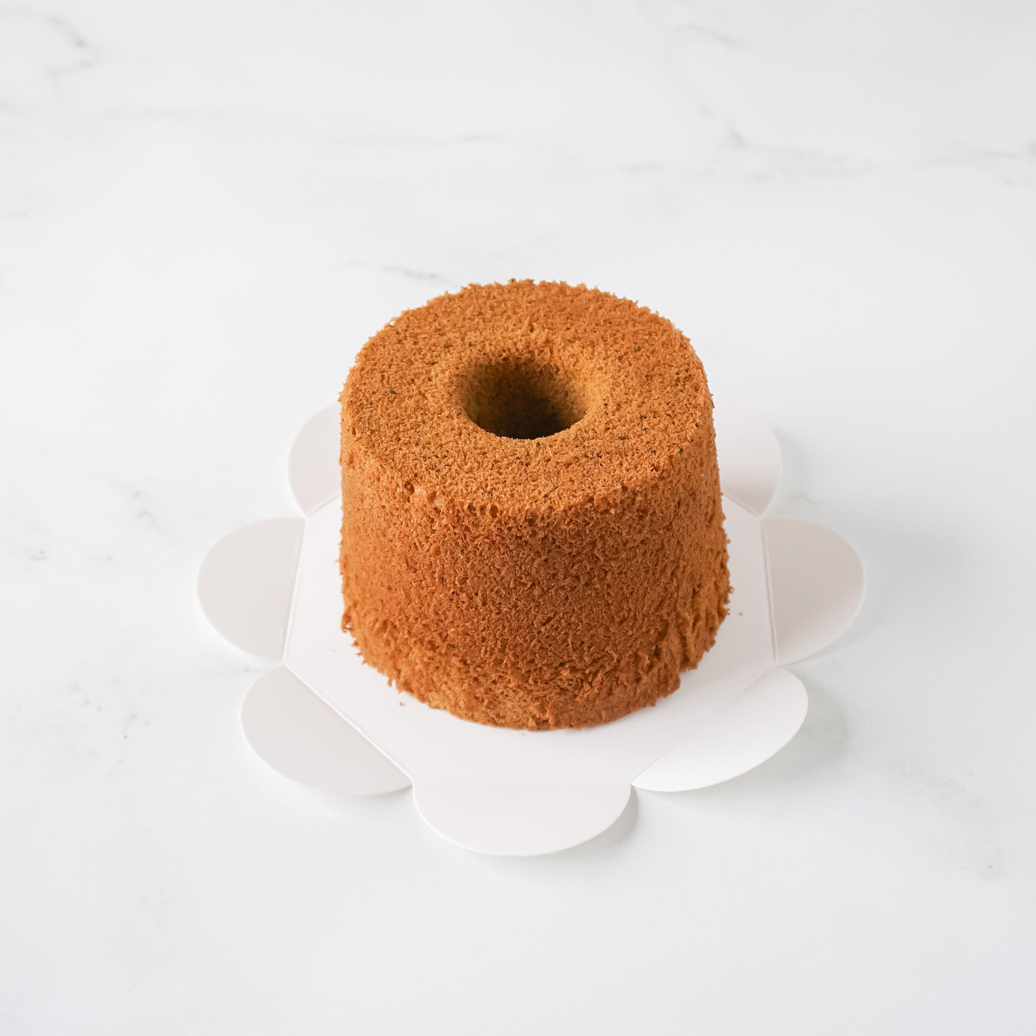 A chiffon cake on a flower-shaped cake board.