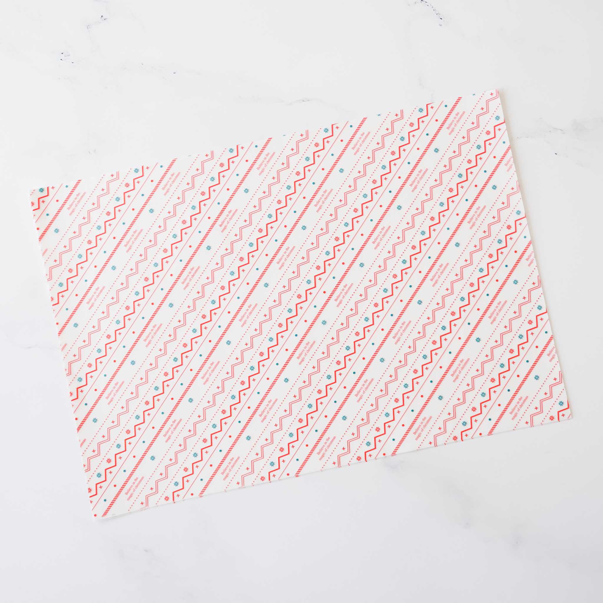 Pink and teal geometric patterned wrapping paper. The design features diagonal lines of repeating zigzags and dots on a white background. This decorative paper is ideal for gift wrapping and crafting projects.