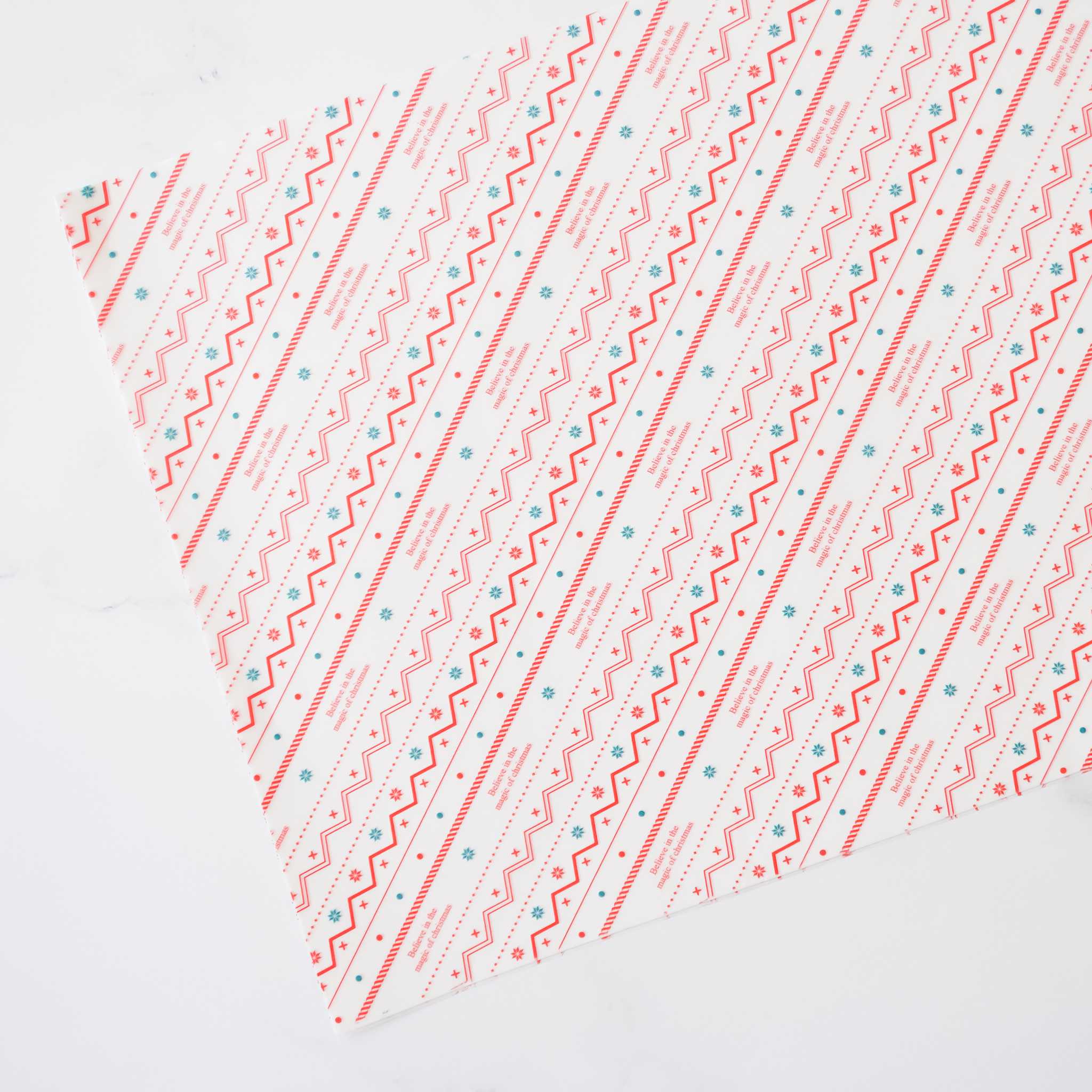 Sheets of deli paper with a festive red, green, and white Nordic print design, pre-cut for food service use.