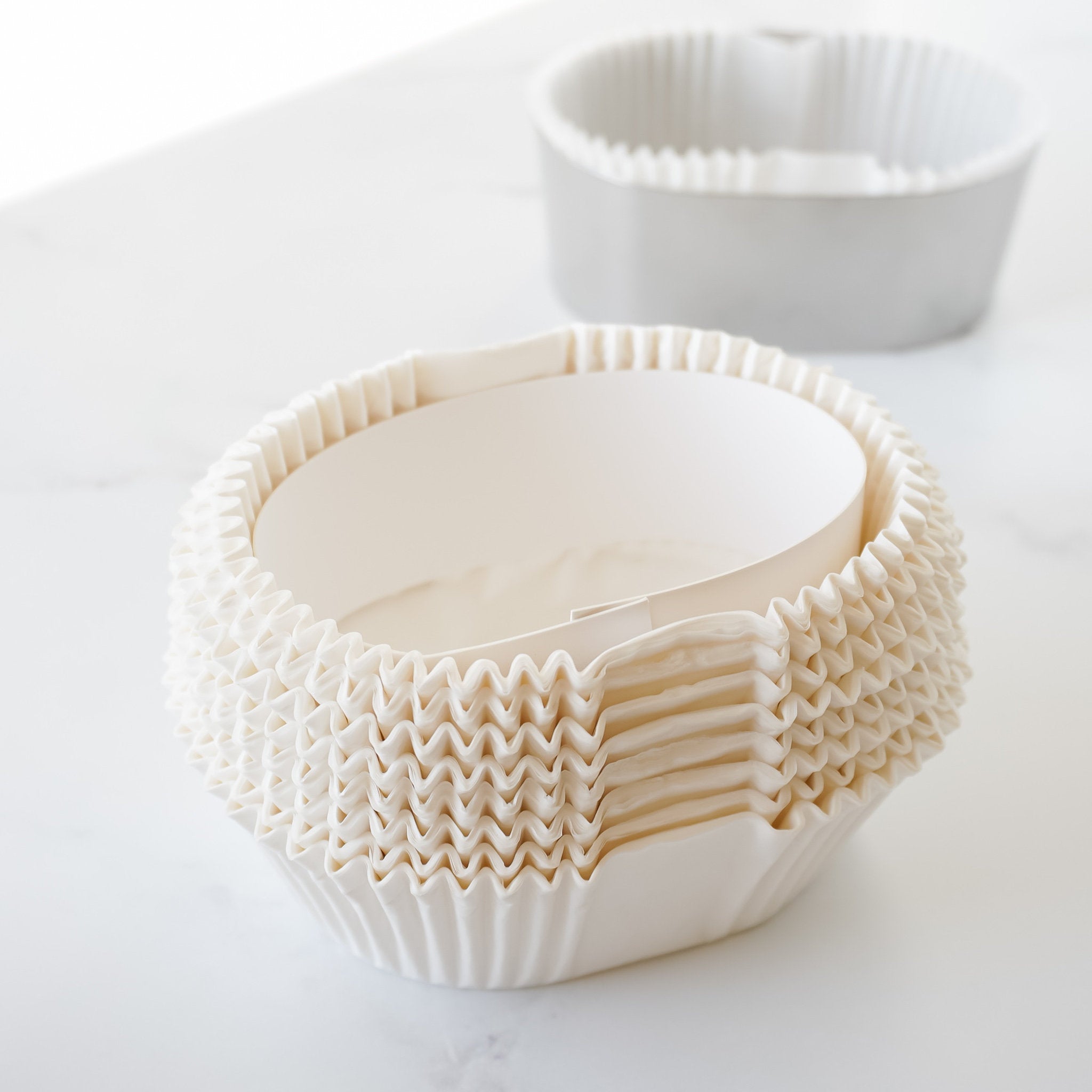 A set of white oval-shaped parchment paper liners for baking, displayed on a light background.