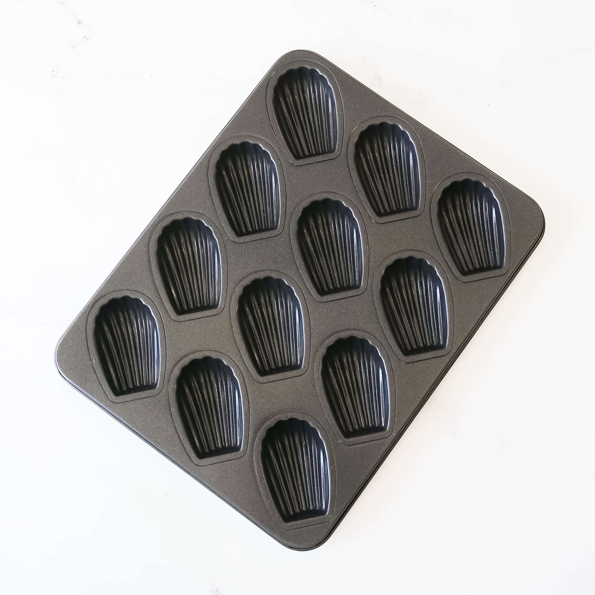A nonstick deep Madeleine pan with 12 cavities on a white background.
