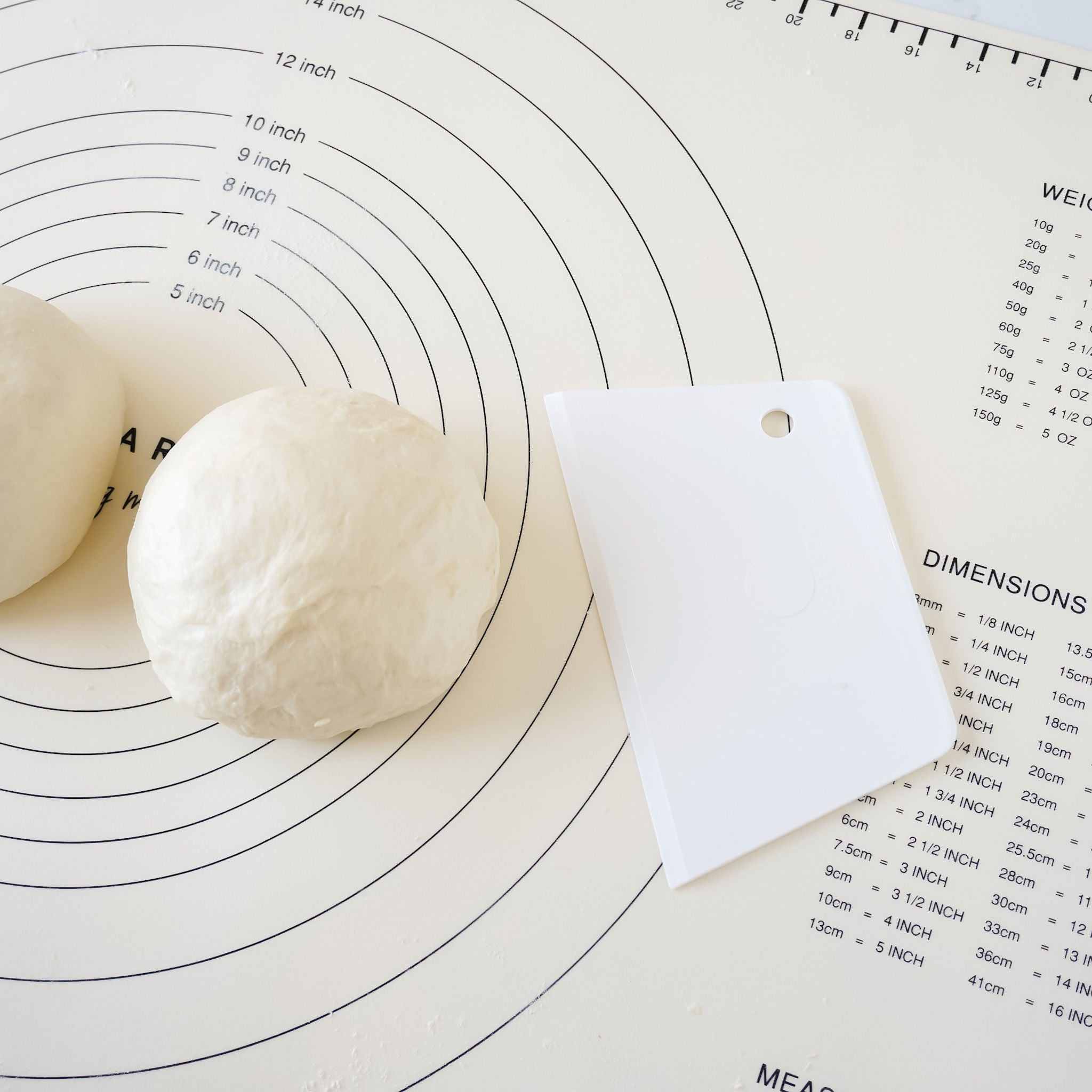 A white dough scraper placed on a surface with a baking chart.