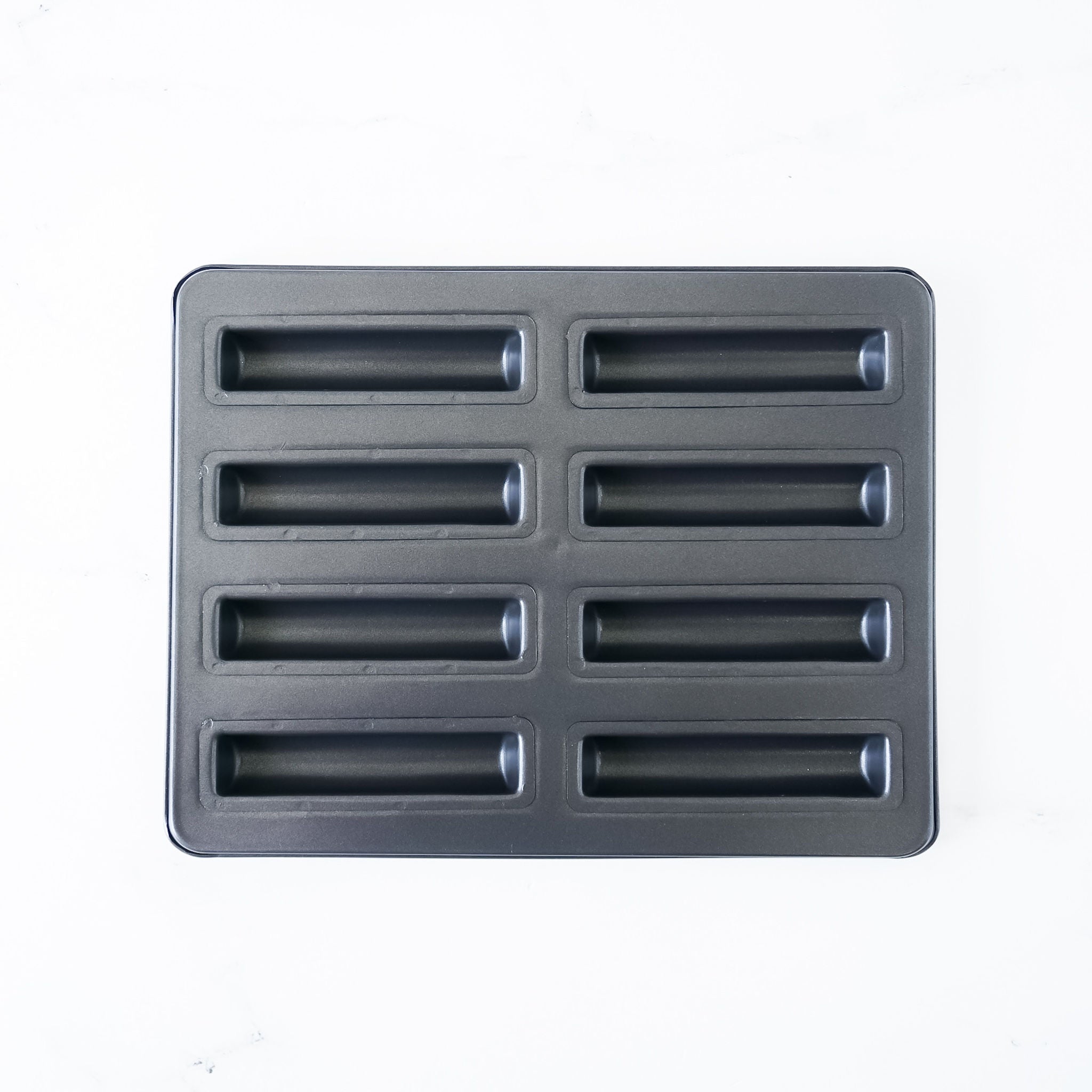 A black financier cake pan with eight cavities, each shaped like a baton. The pan is made of cold-rolled steel with a nonstick coating.