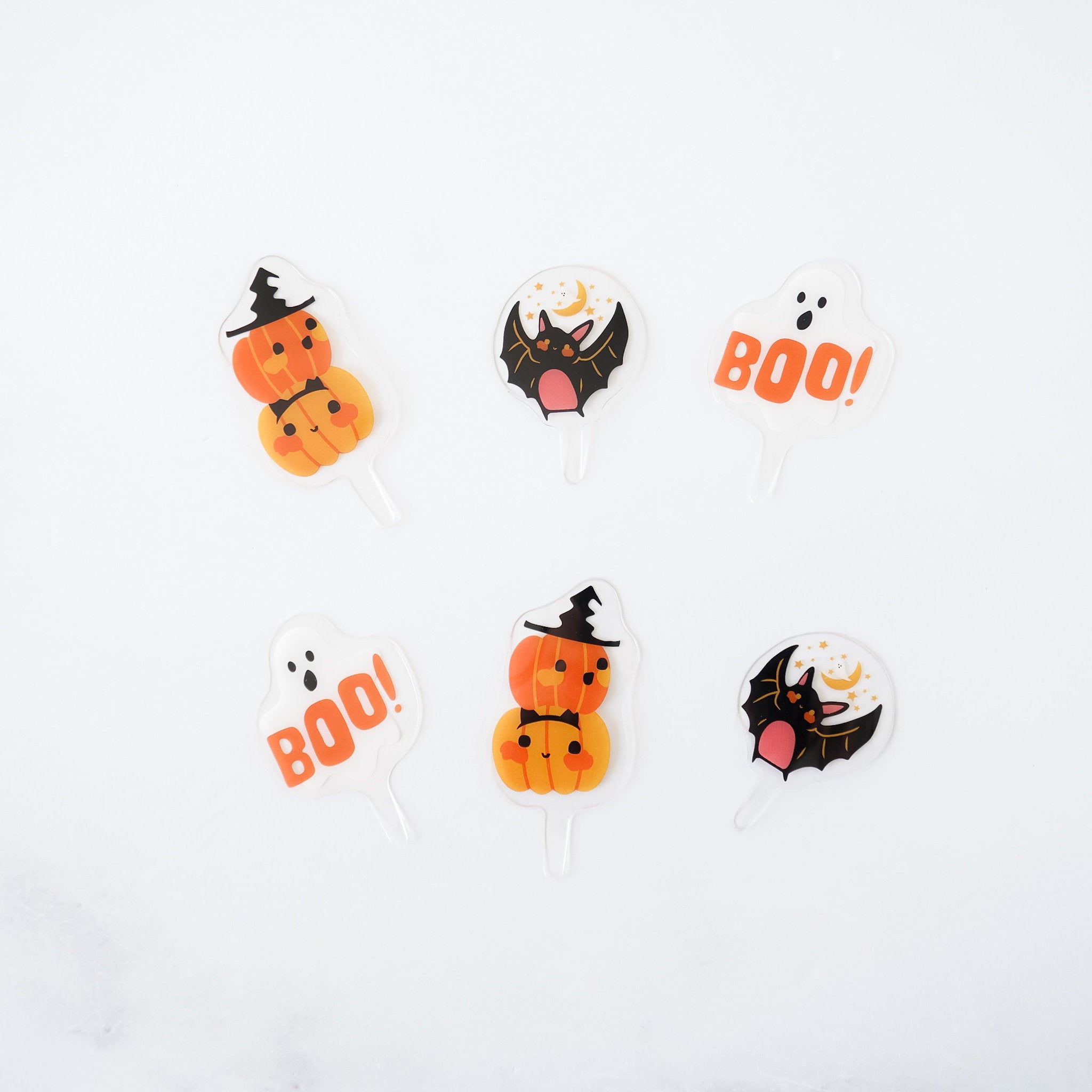 A set of Halloween cupcake toppers with three designs: a pumpkin, a ghost, and a bat.