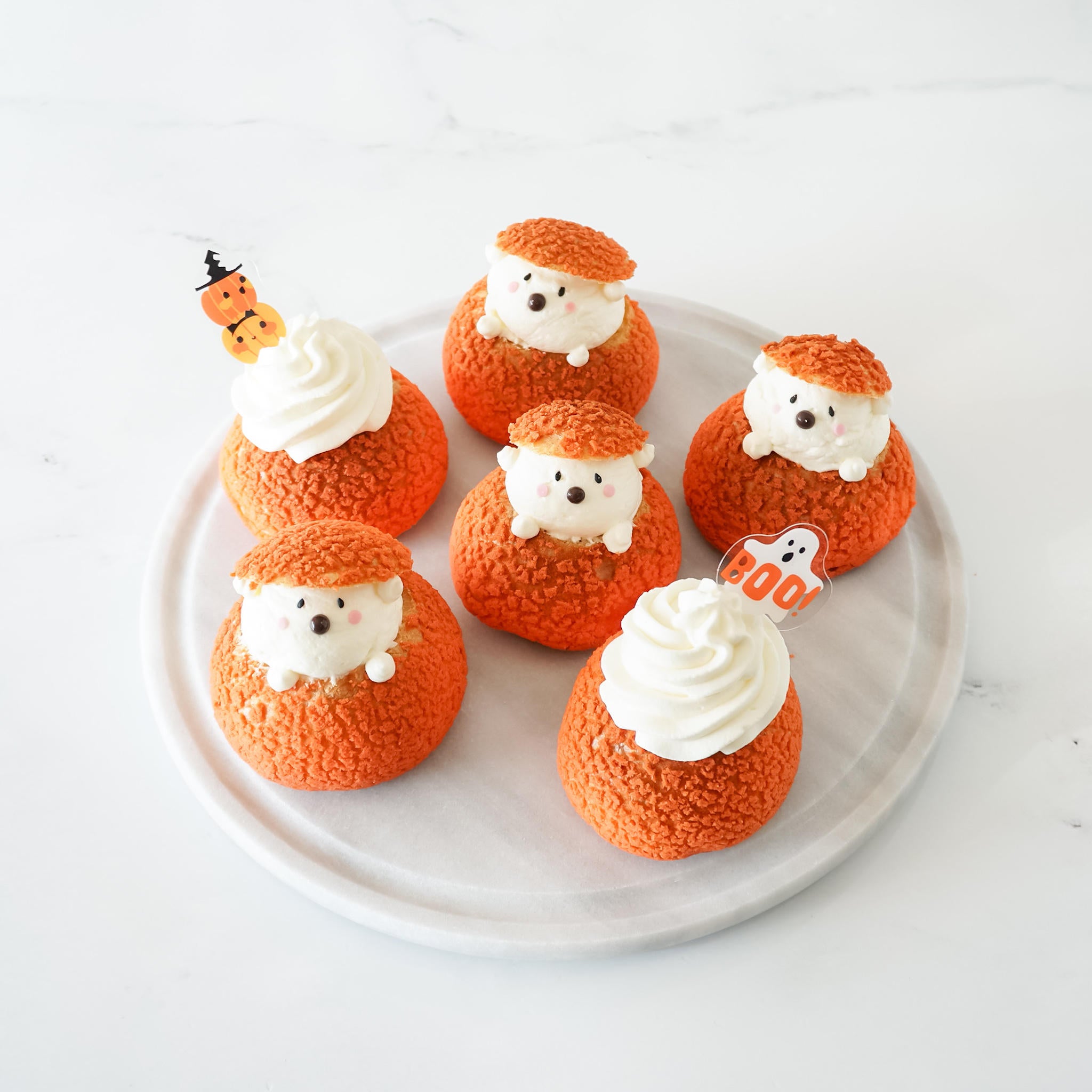 A set of Halloween cupcake toppers with three designs: a pumpkin, a ghost, and a bat, displayed on a plate.