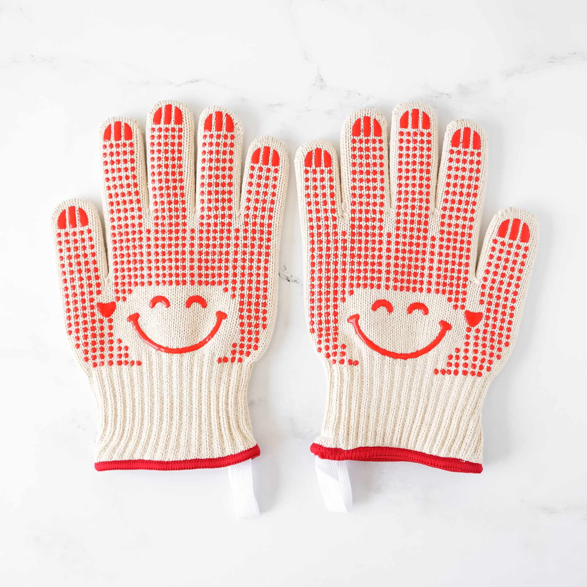 Pair of oven gloves with smiley face design on a white background