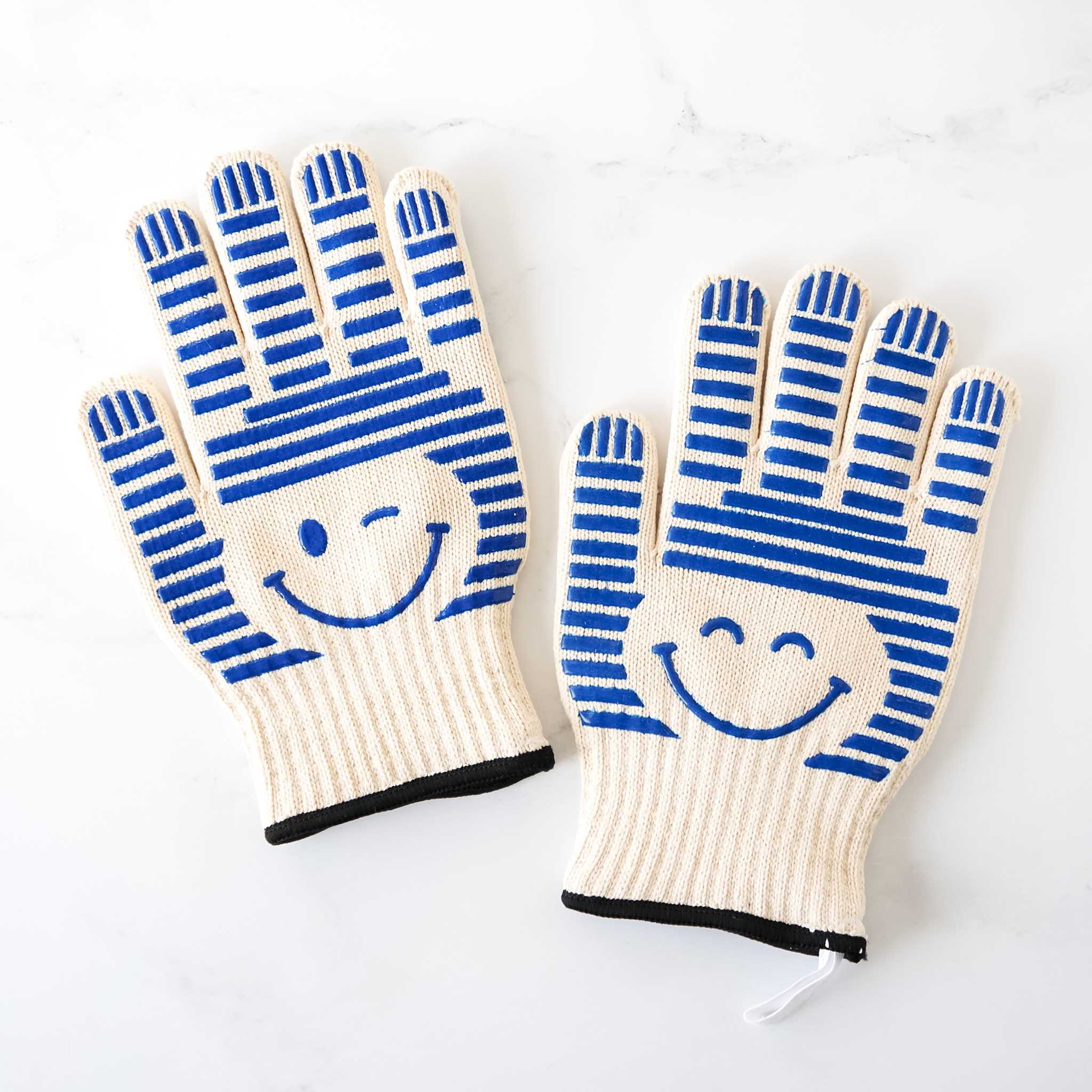 A pair of heat resistant oven gloves with blue stripes and a smiley face design on the back.