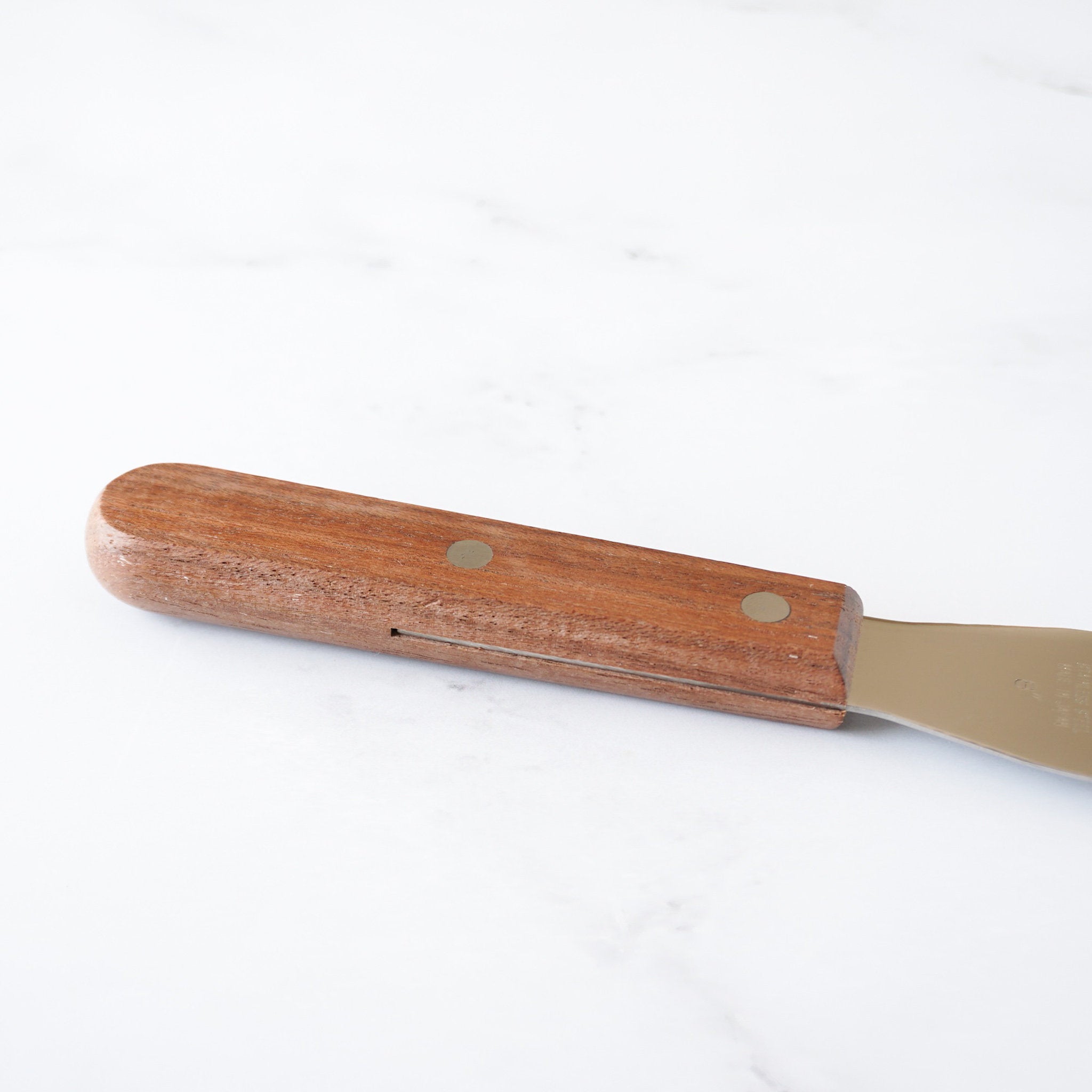 A wooden handled metal spatula with a brown wooden handle and a silver metal blade.