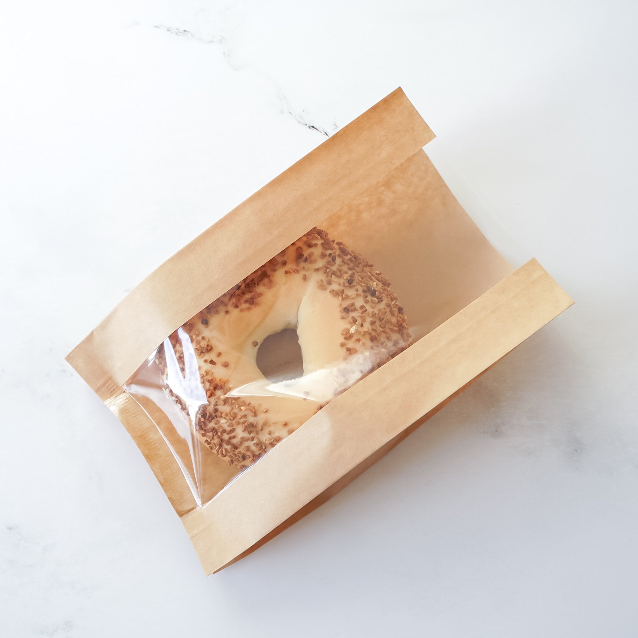 Bagels in a brown paper bag on a white background