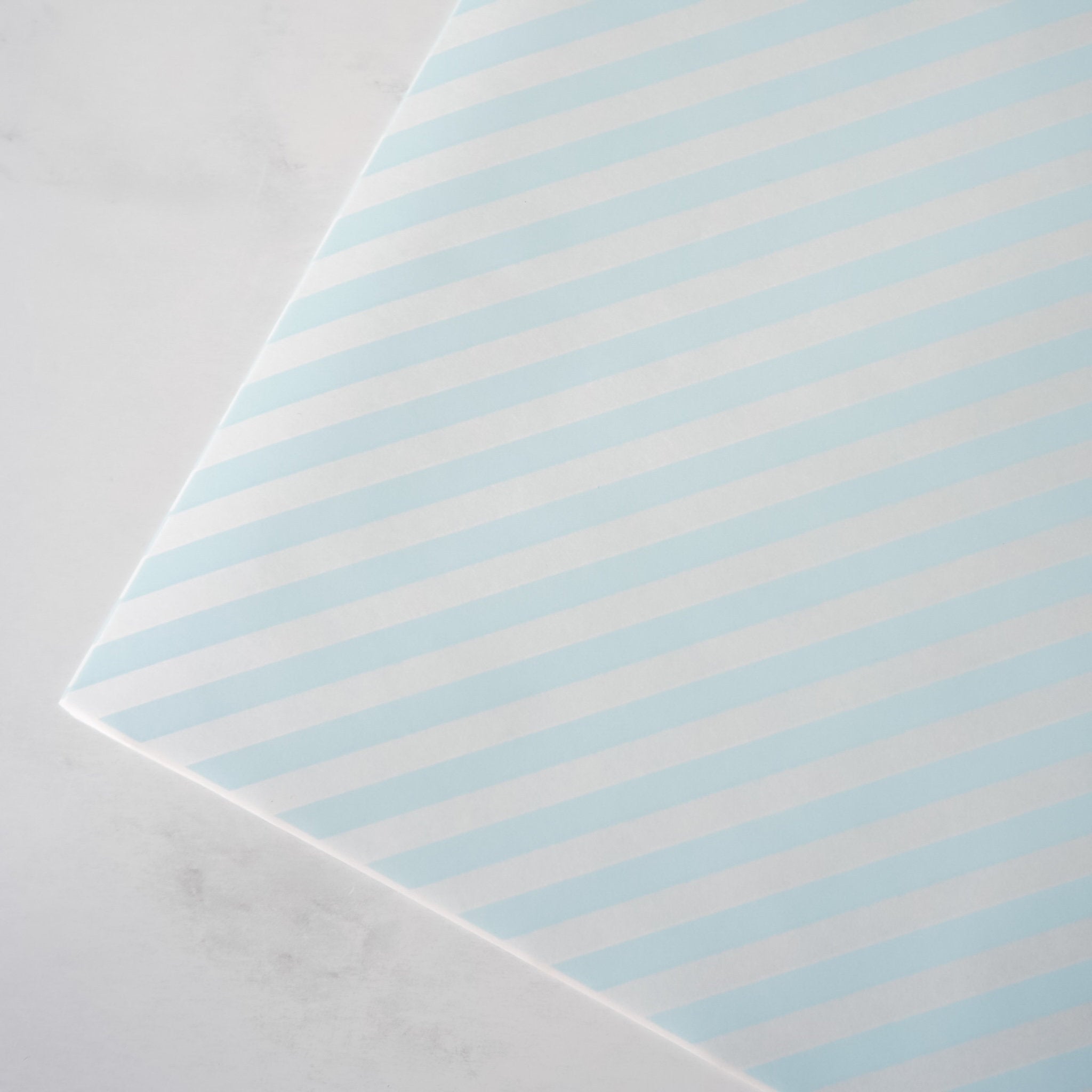 Striped deli paper with light blue and white stripes on a gray background