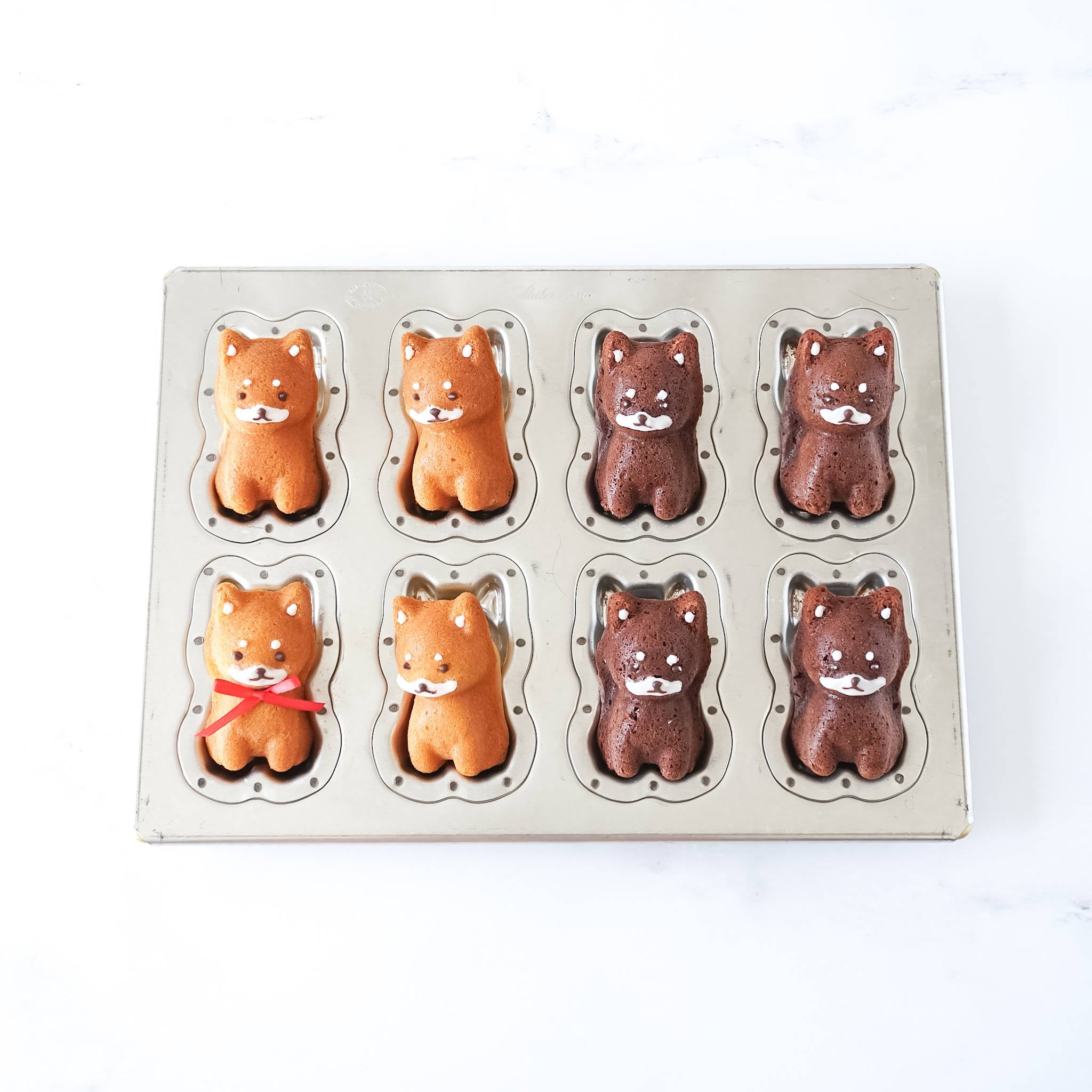 A silicone-coated madeleine pan with dog-shaped cavities, resembling Shiba Inu, on a white background.