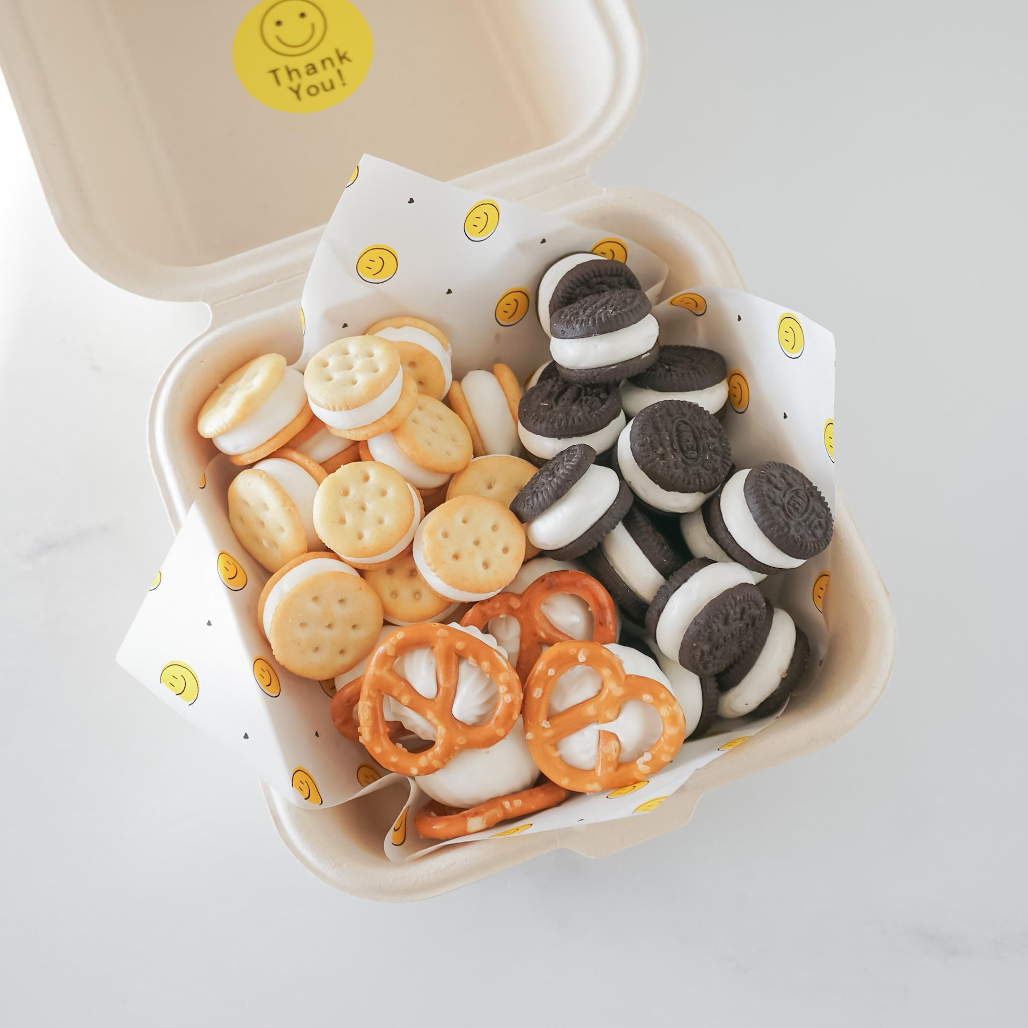 Meringue cookies on mini smile deli paper with yellow smiley face patterns on a white background, placed on a white surface.
