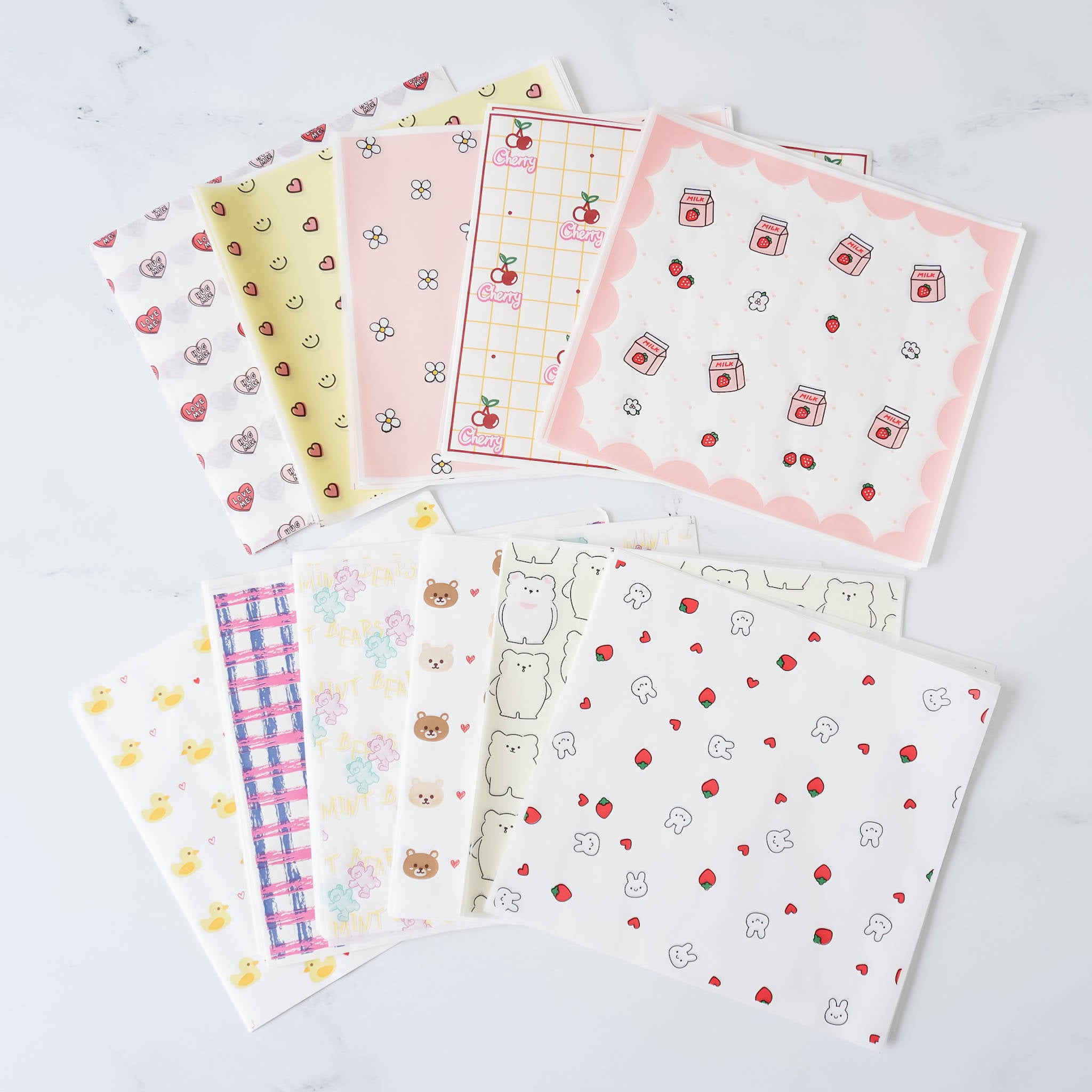 Assorted deli papers with various patterns including dots, animals, and geometric designs, displayed on a marble surface.
