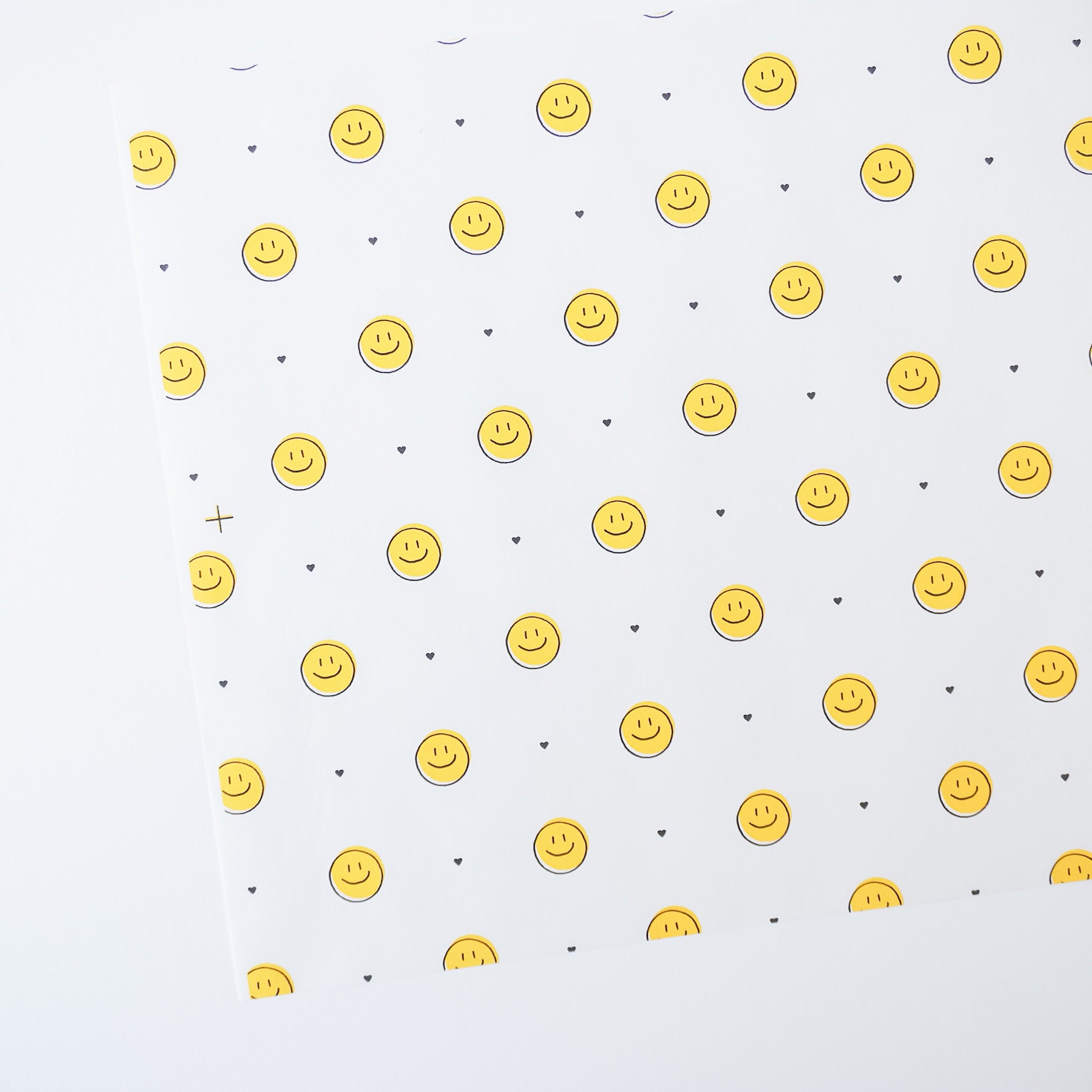 A sheet of mini smile deli paper with yellow smiley face patterns on a white background, placed on a white surface.