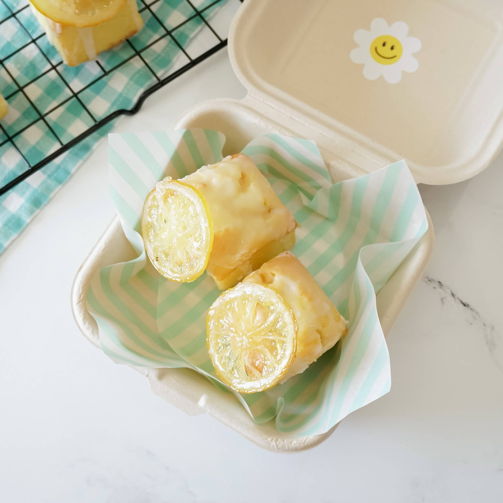 Sheets of mint stripe deli paper wrapped around a sandwich, placed on a plate with a cooling rack in the background.