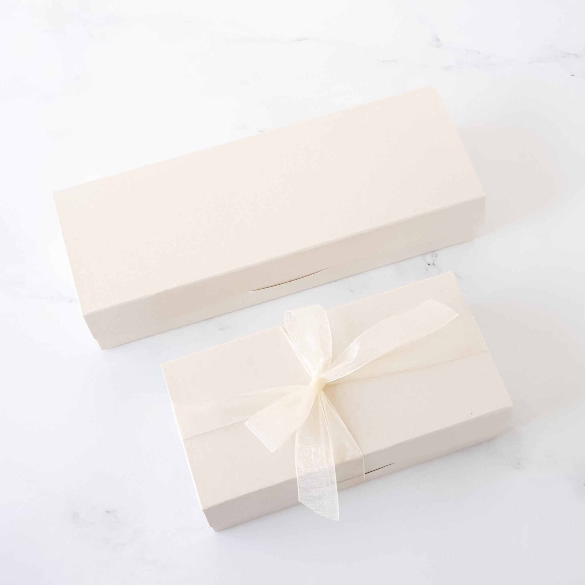 Two beige gift boxes with ribbons on a white background