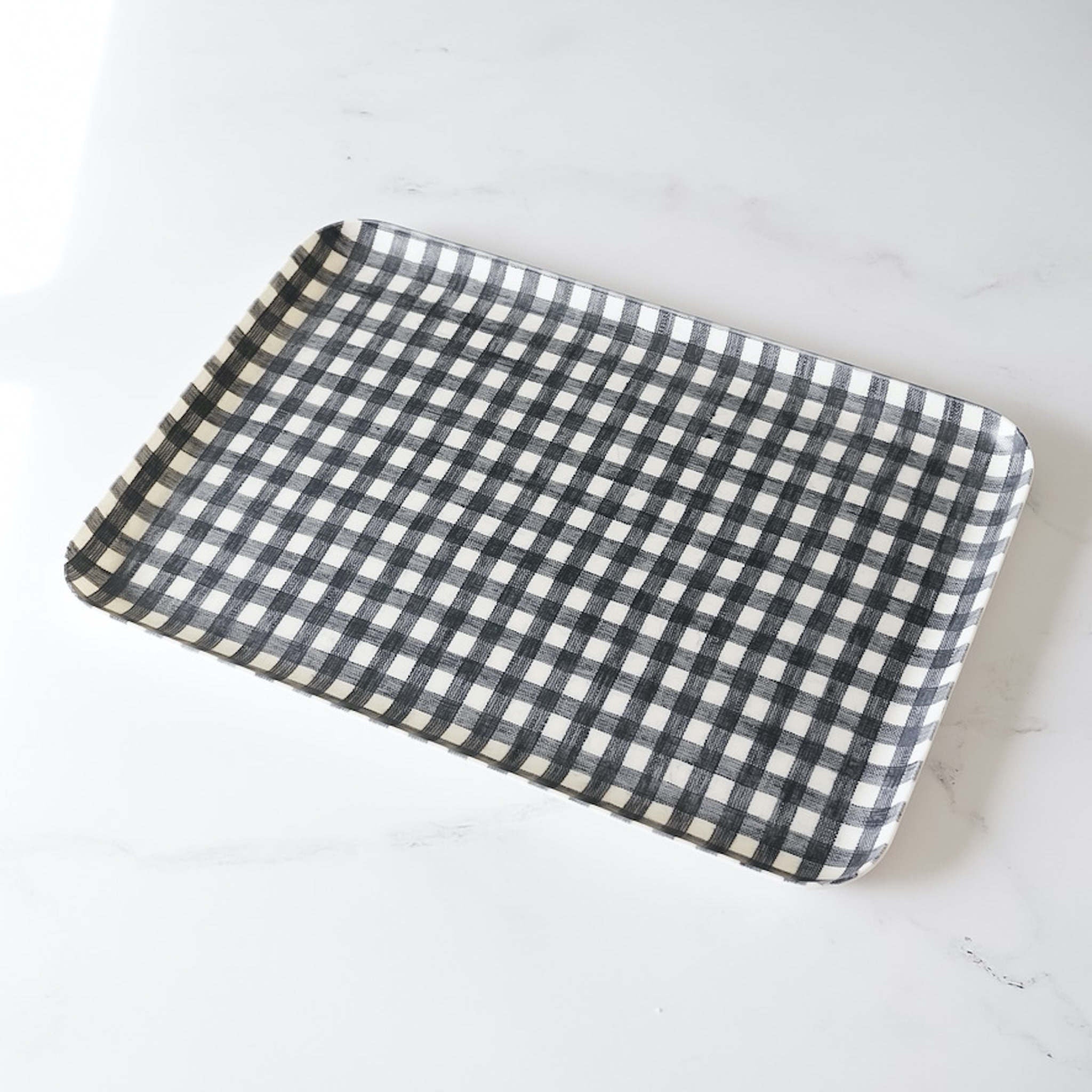 A dark navy check linen coated tray placed on a white surface.