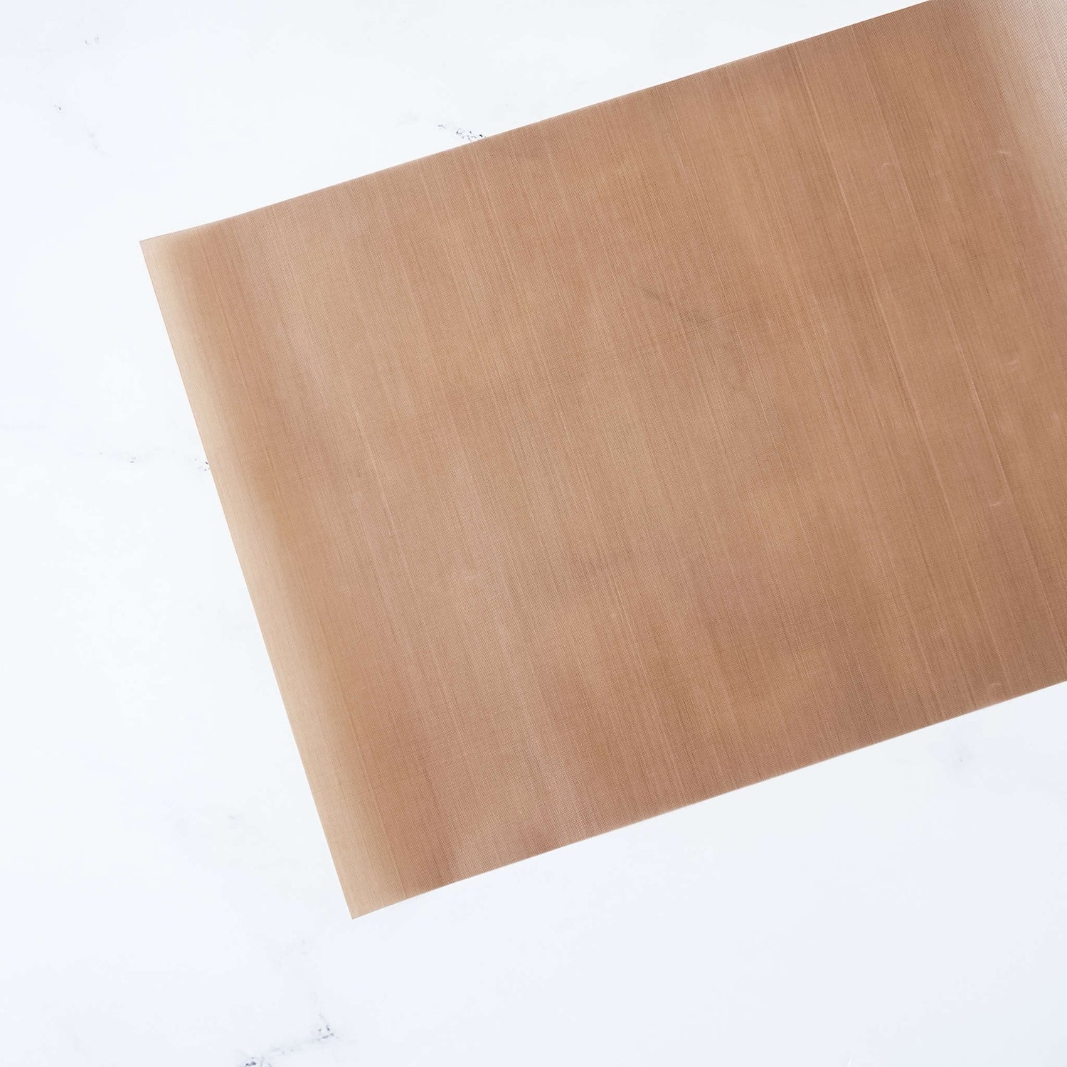 A Teflon sheet with a non-stick surface, beige in color, placed on a white background.