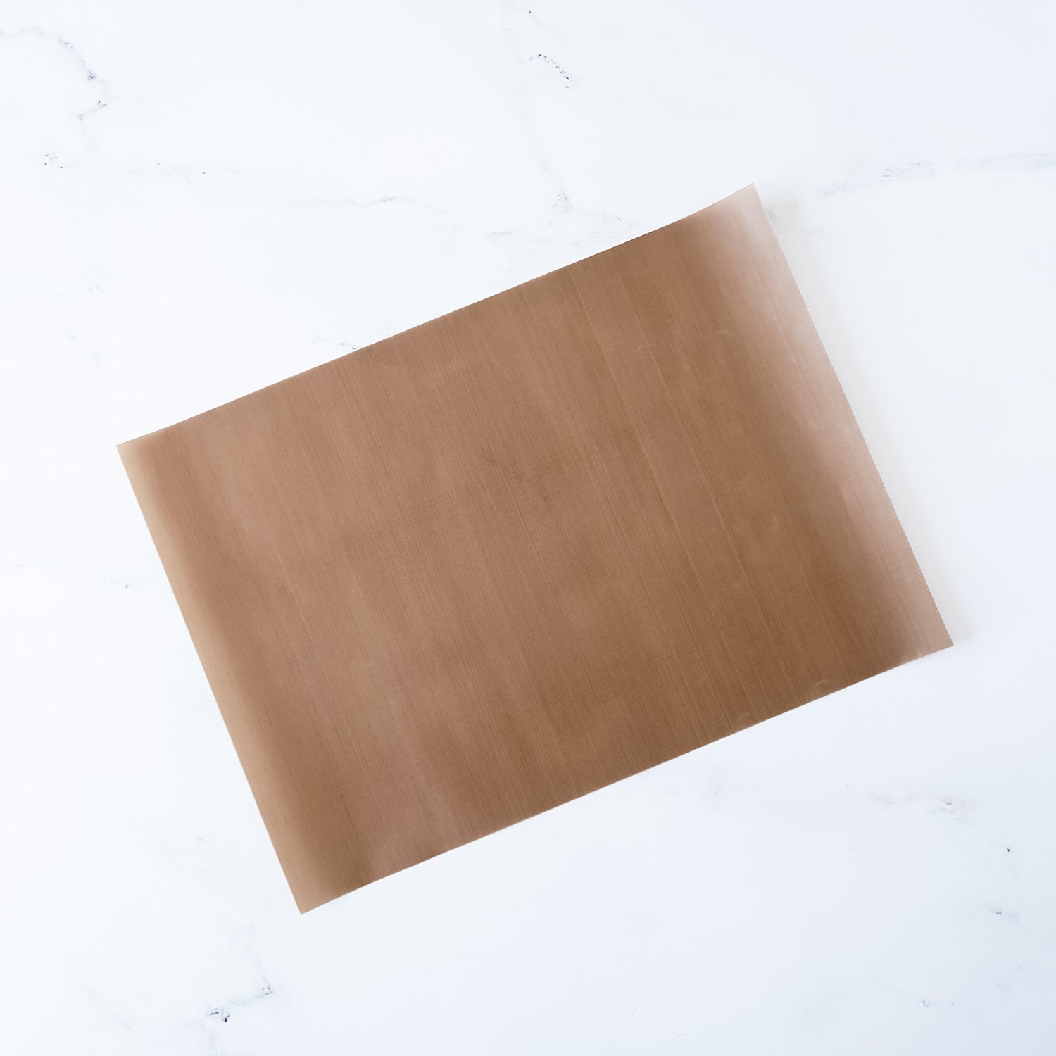 A Teflon sheet with a non-stick surface, beige in color, placed on a white background.