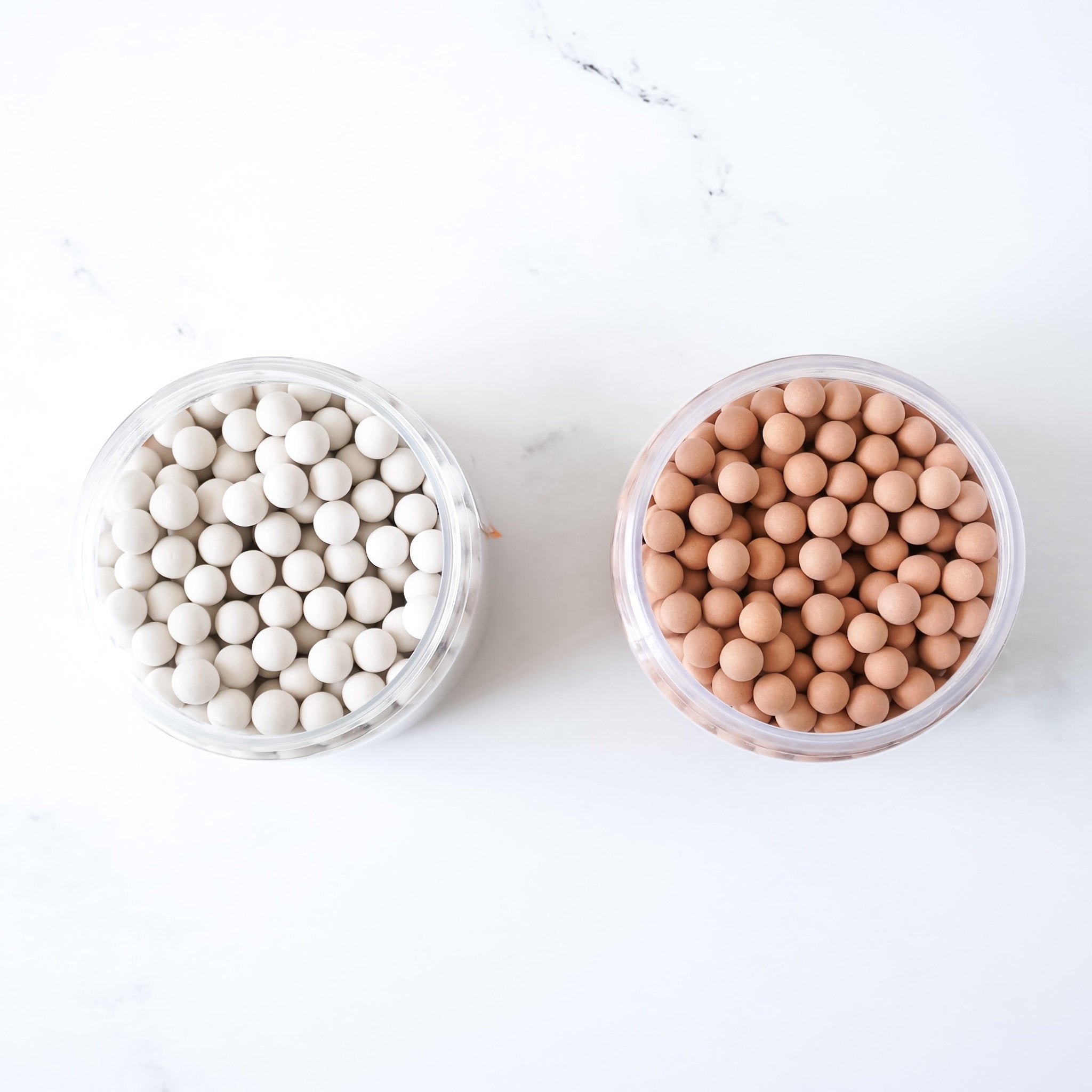 Two containers of ceramic pie weights on a white background
