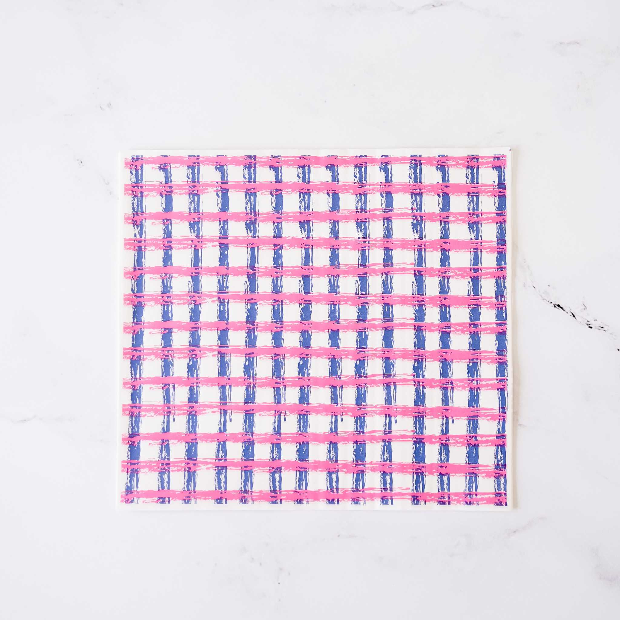 A white sheet of paper with a pink and blue gingham pattern. The pattern is made of thin, brushstroke-like lines.