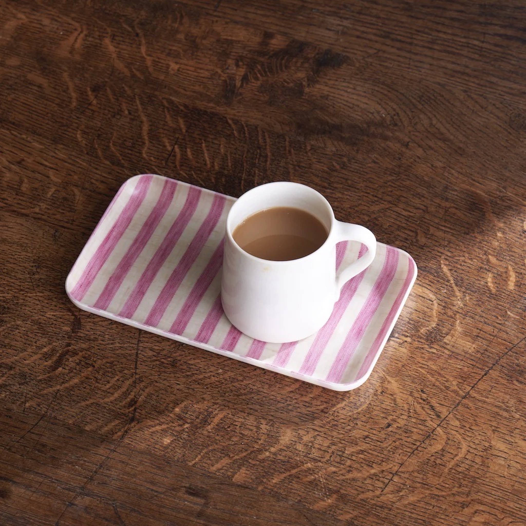 a cup of coffee on a pink tray