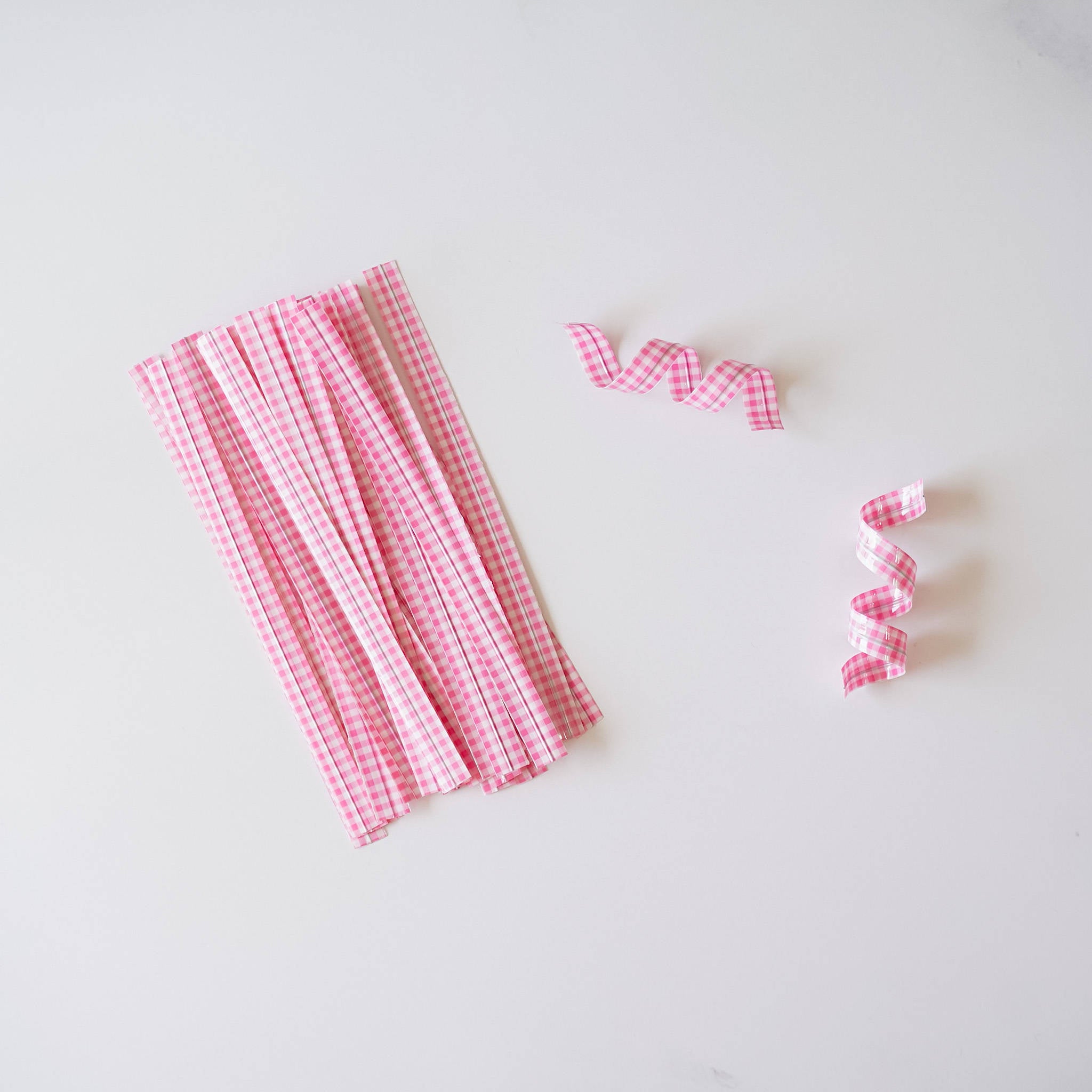 Pink gingham check twist ties arranged on a white surface.