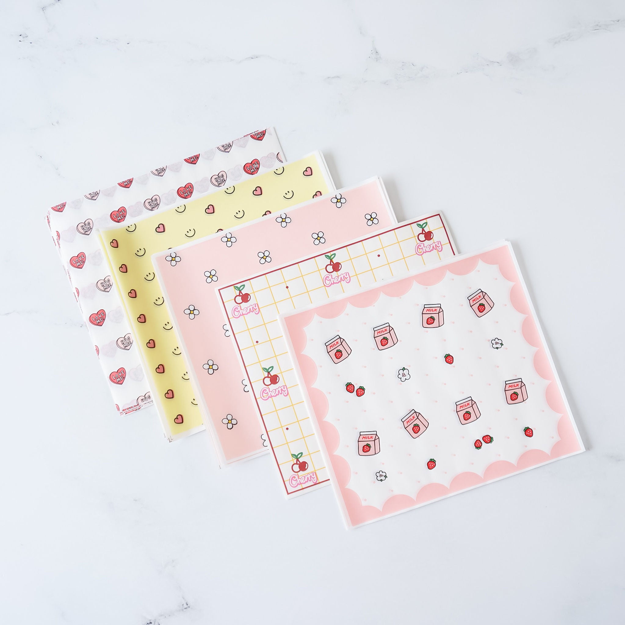 Assorted deli papers with various patterns including dots, animals, and geometric designs, displayed on a marble surface.i