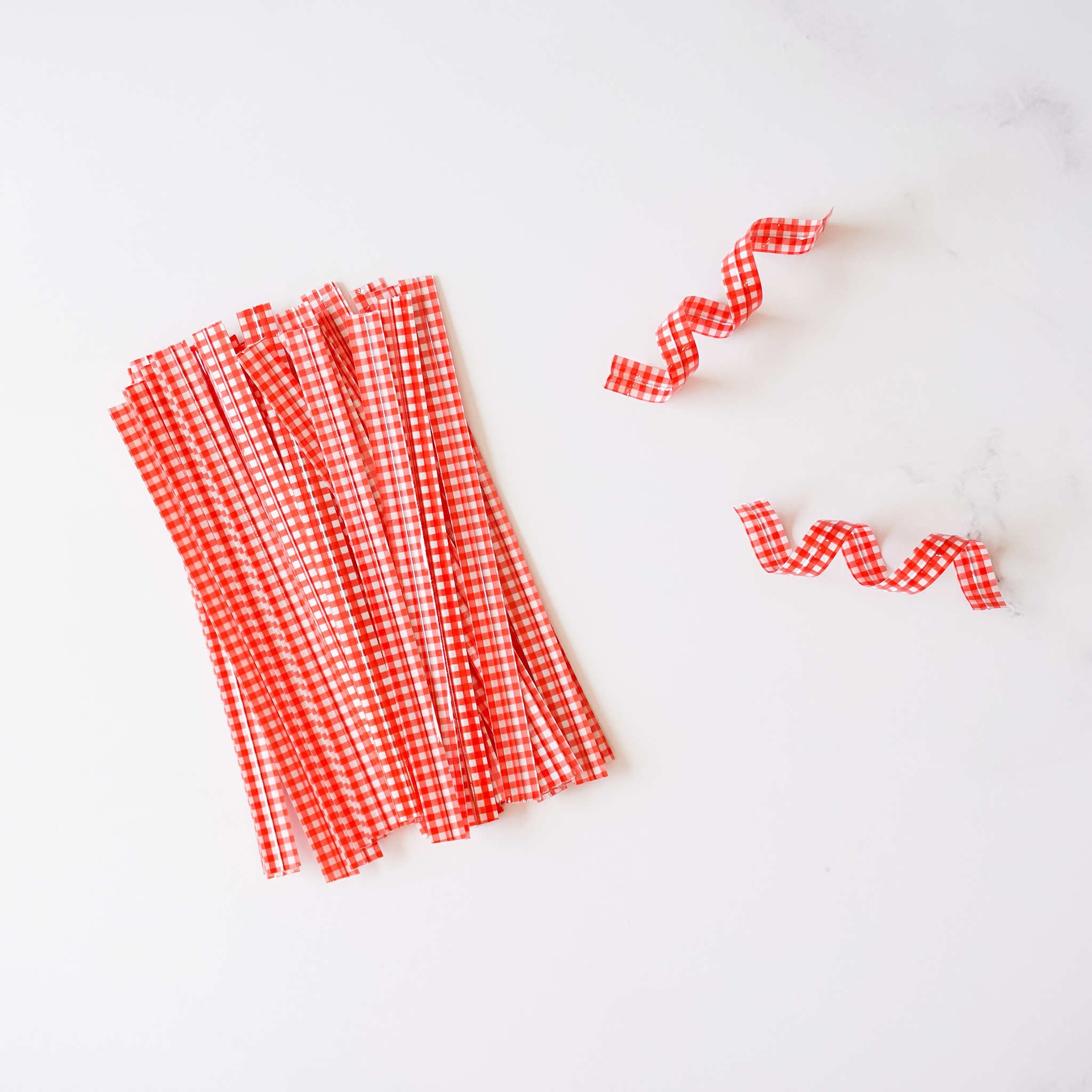 Red gingham check twist ties arranged on a white surface.