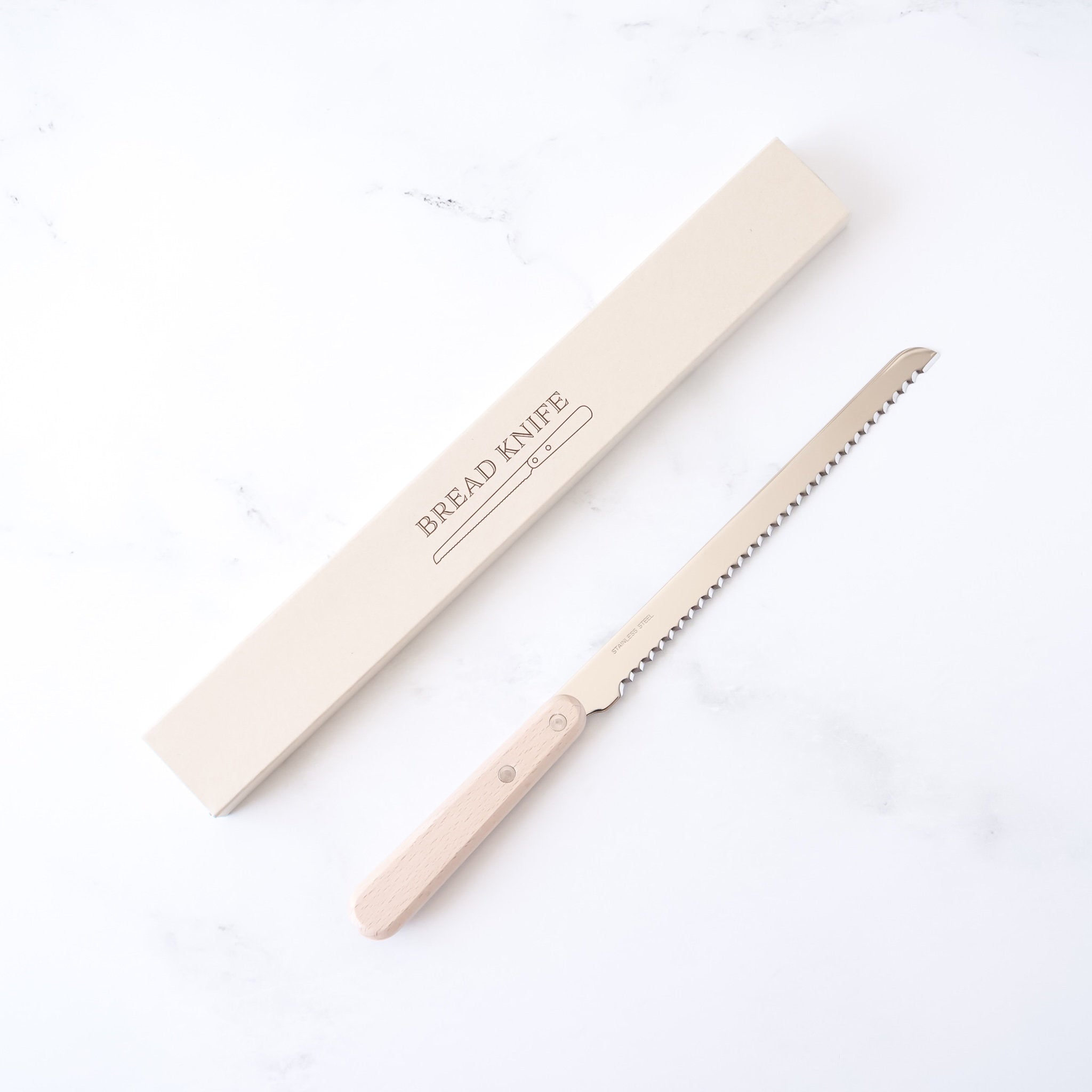 A compact bread knife with a wooden handle and a serrated stainless steel blade, accompanied by its packaging box, displayed on a white background.