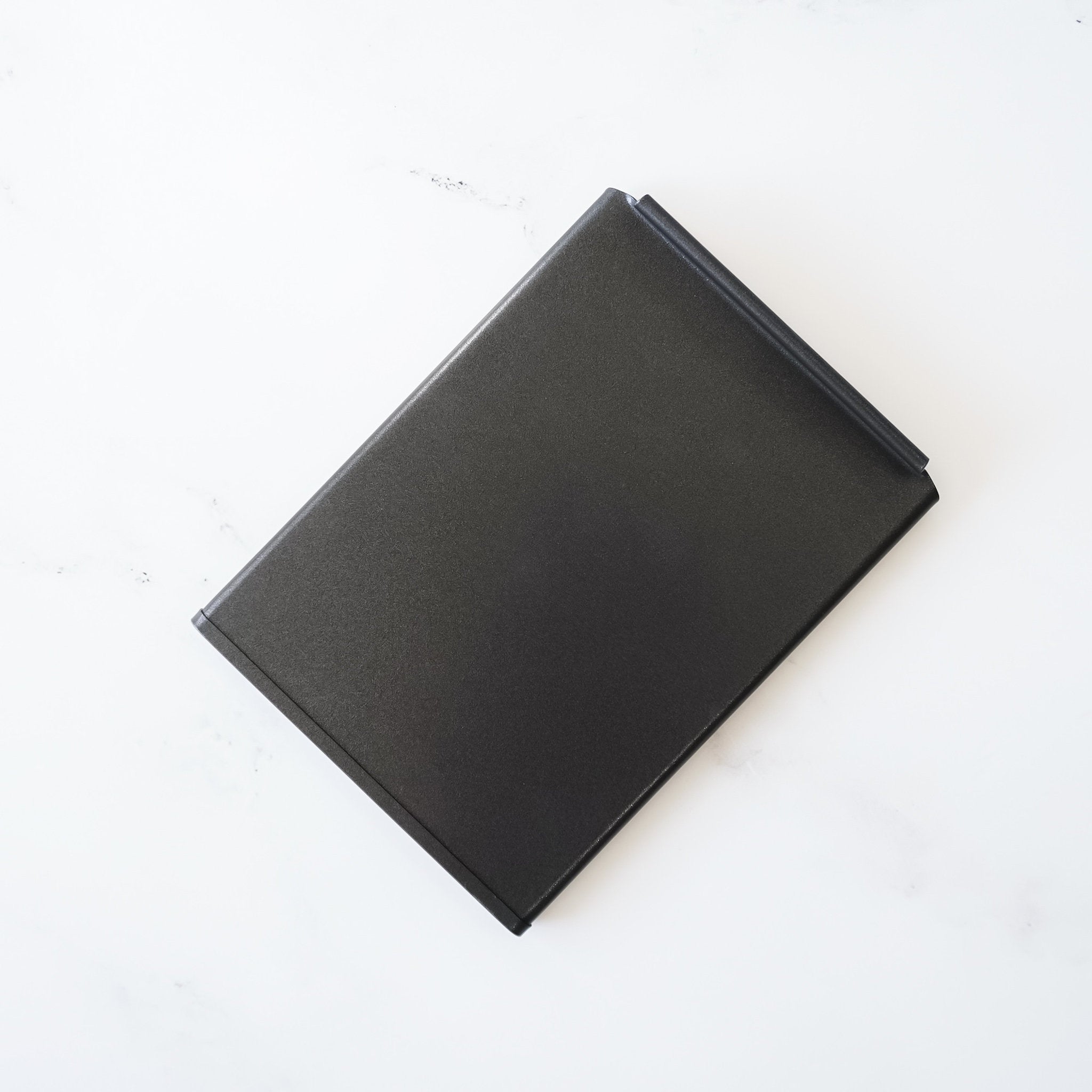 A black rectangular lid with a slightly curved edge.