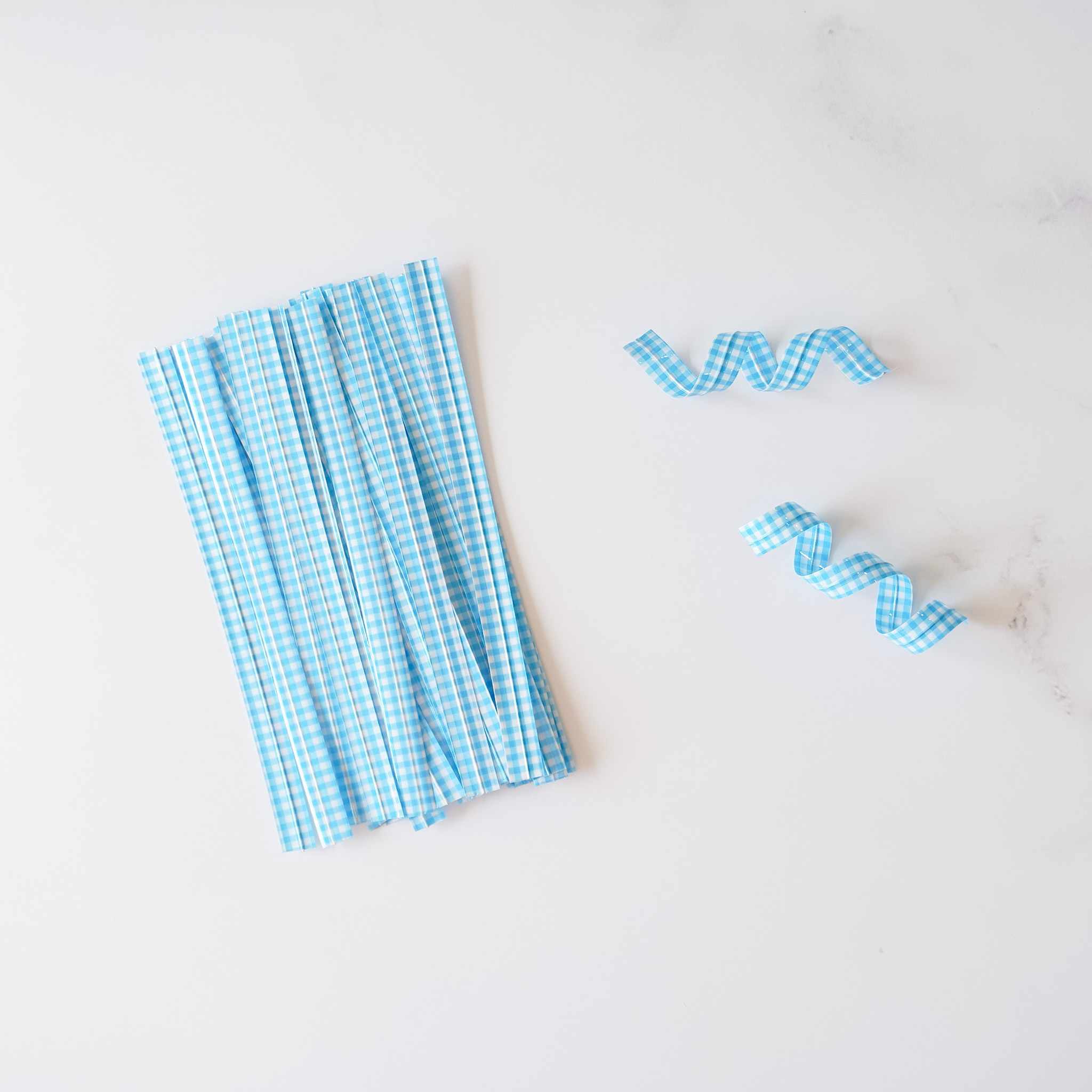Sky blue gingham check twist ties arranged on a white surface.