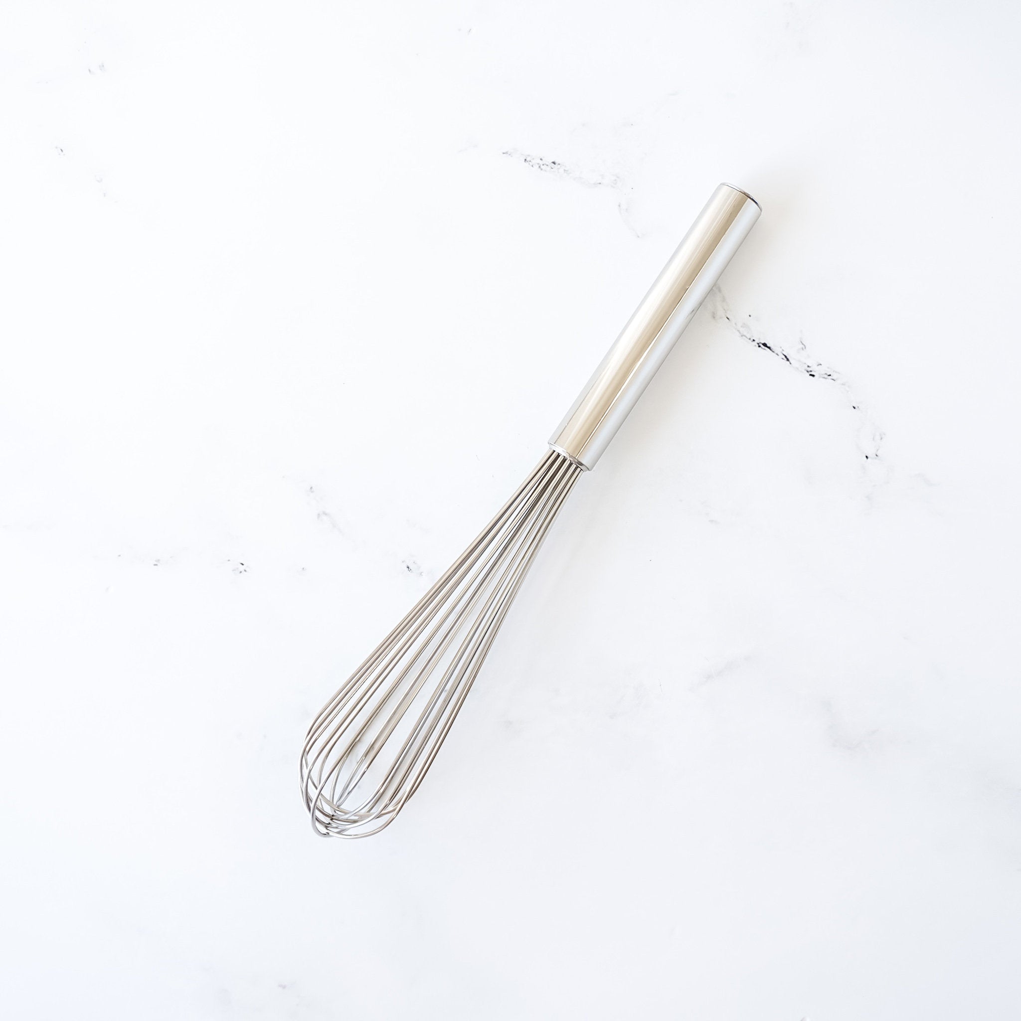 A silver-colored slim wire whisk on a white background.