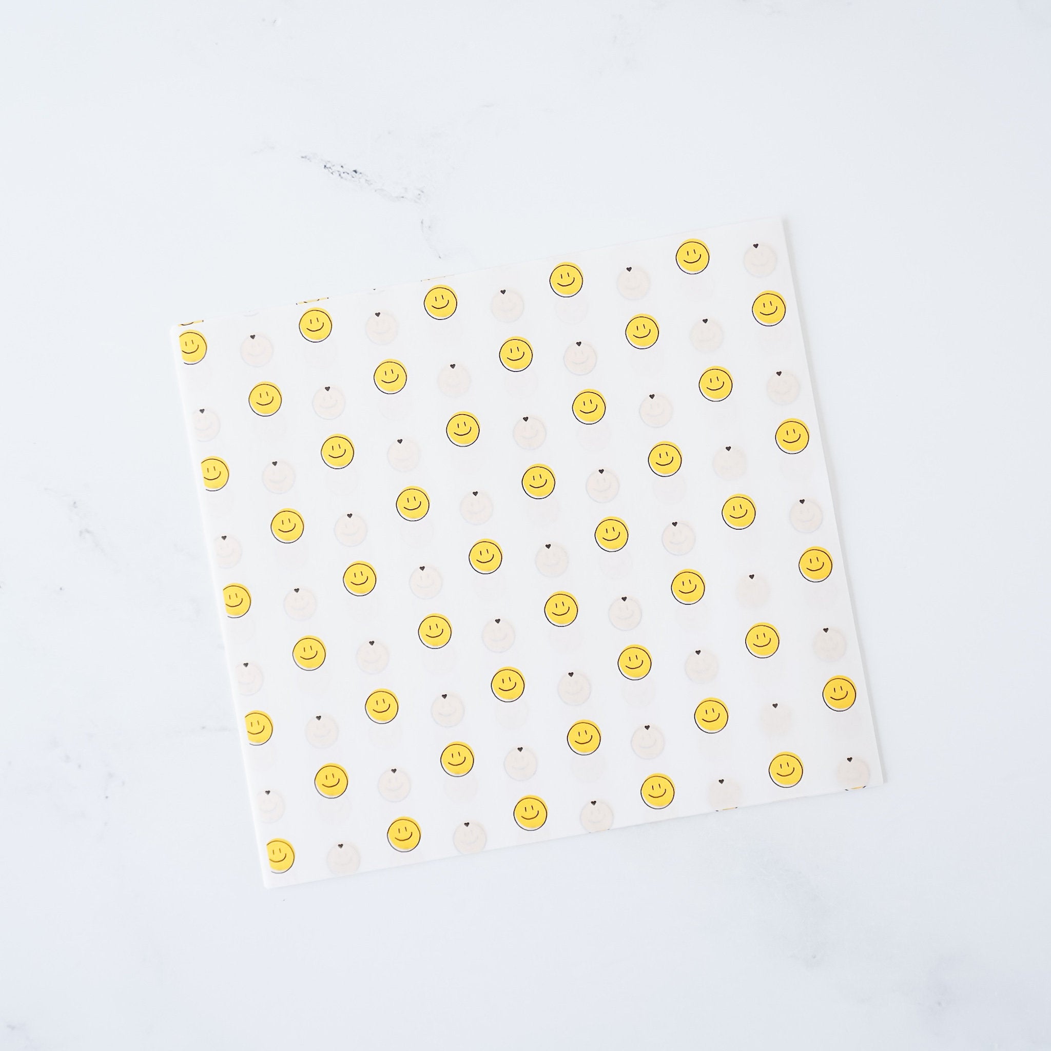 A sheet of mini smile deli paper with yellow smiley face patterns on a white background, placed on a white surface.