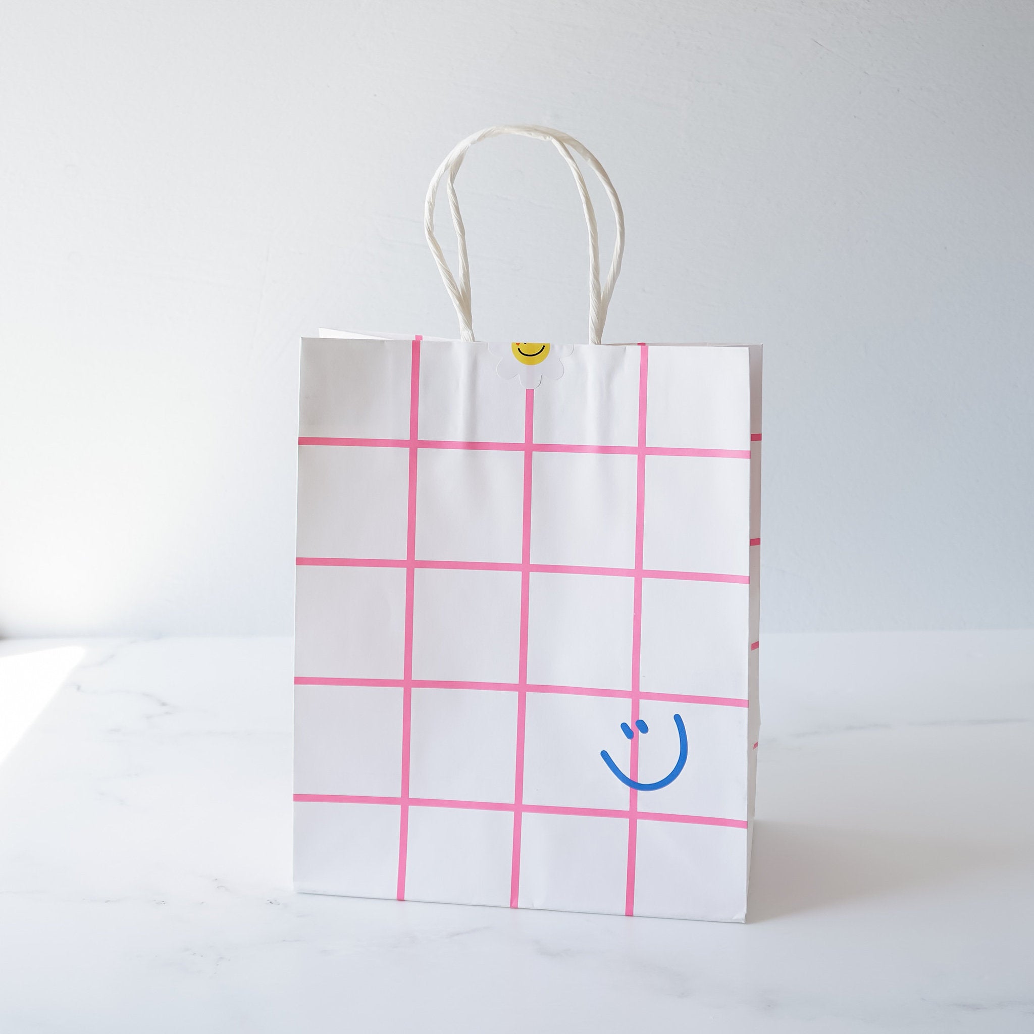 smiley face printed paper bag in pink