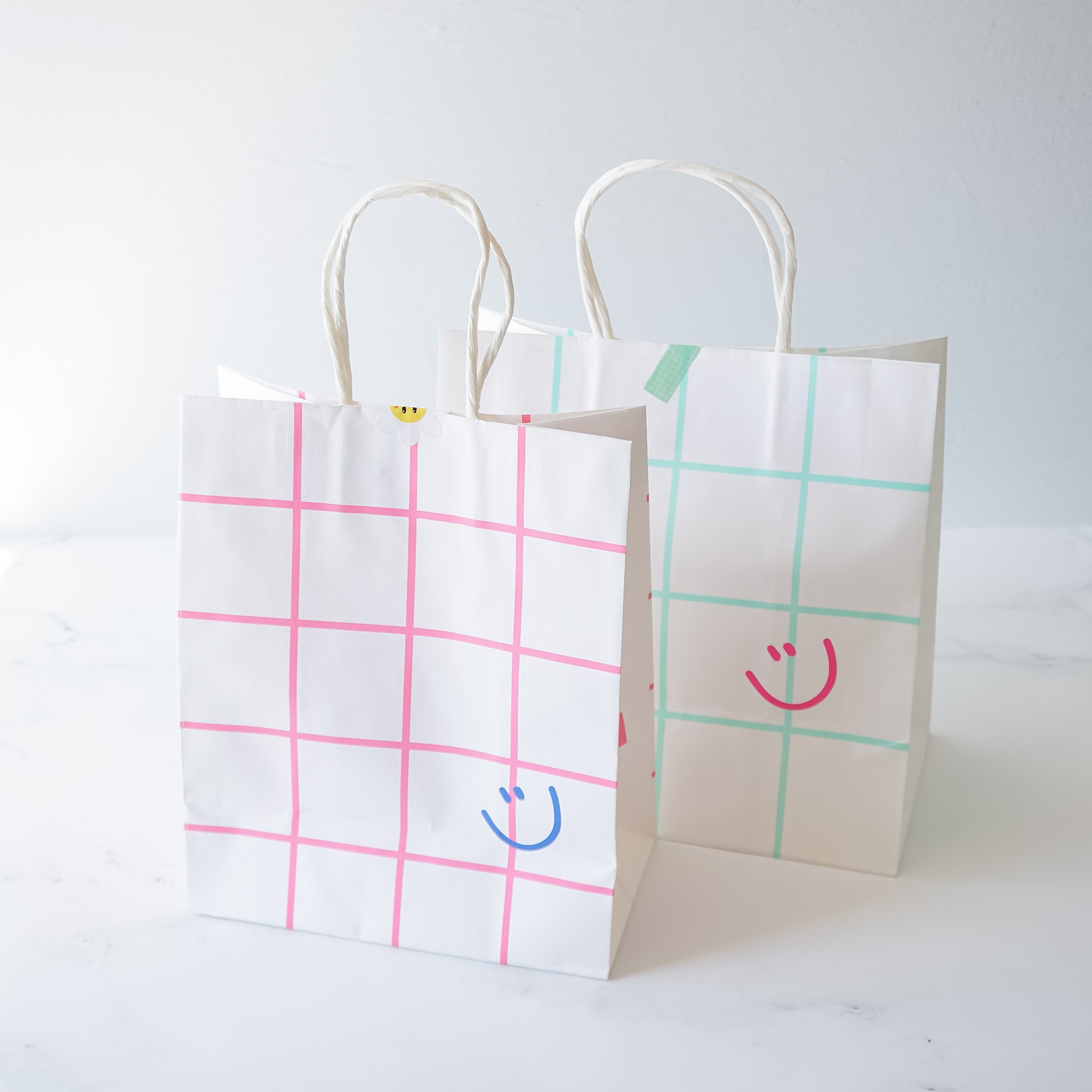 smiley face printed paper bags in pink and mint