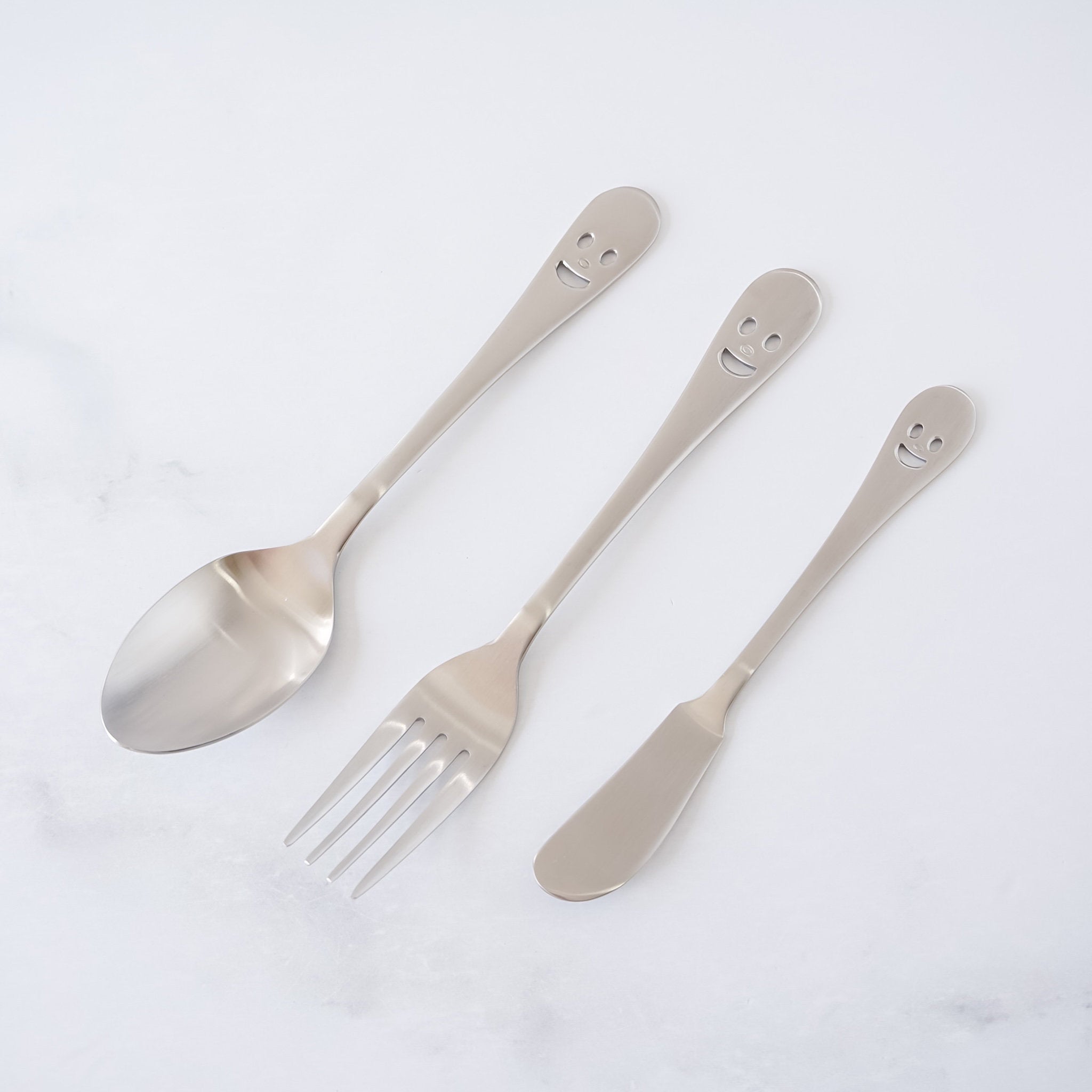 Set of silver smiley face cutlery on a white background