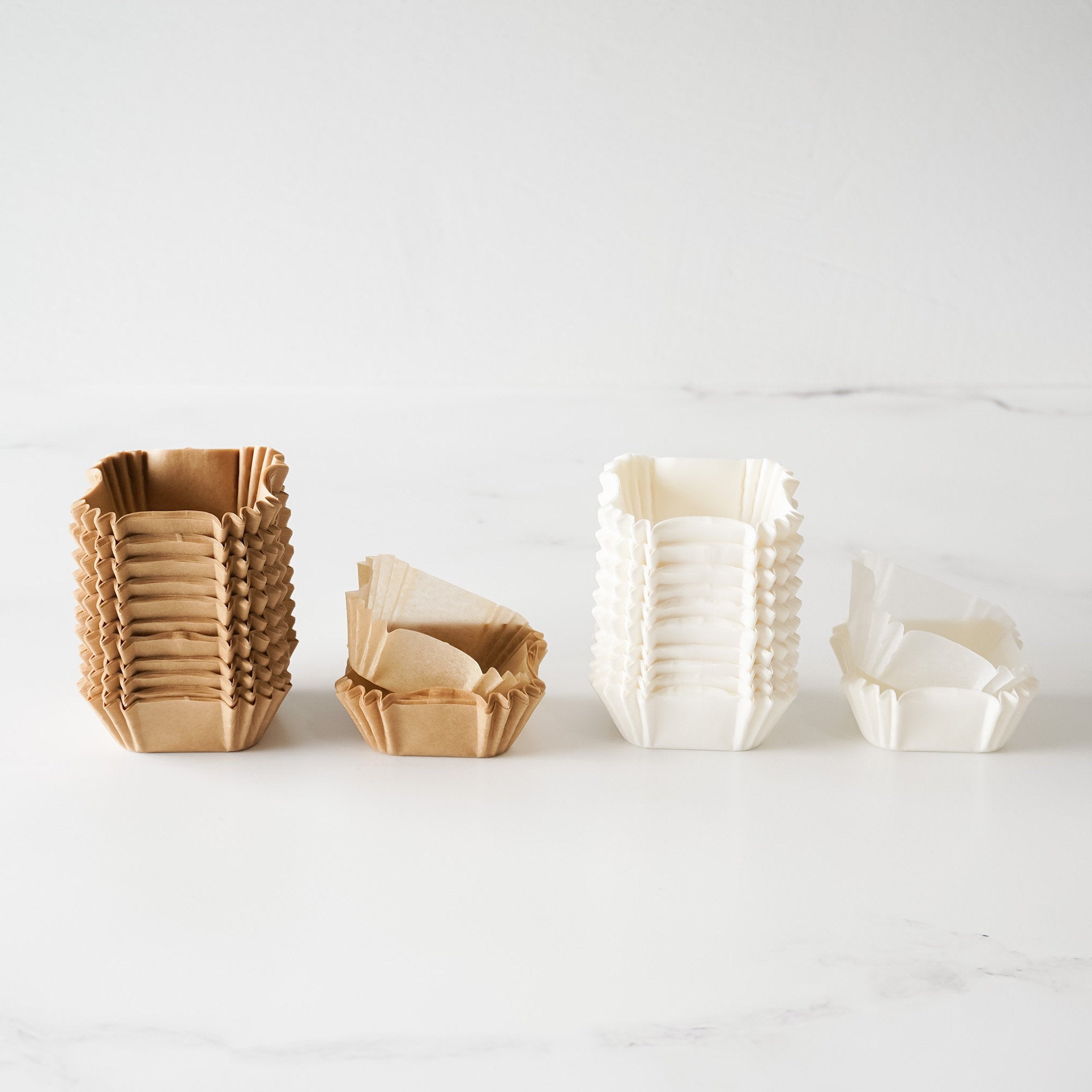 A set of square cupcake liners in kraft and white colors displayed on a light background.
