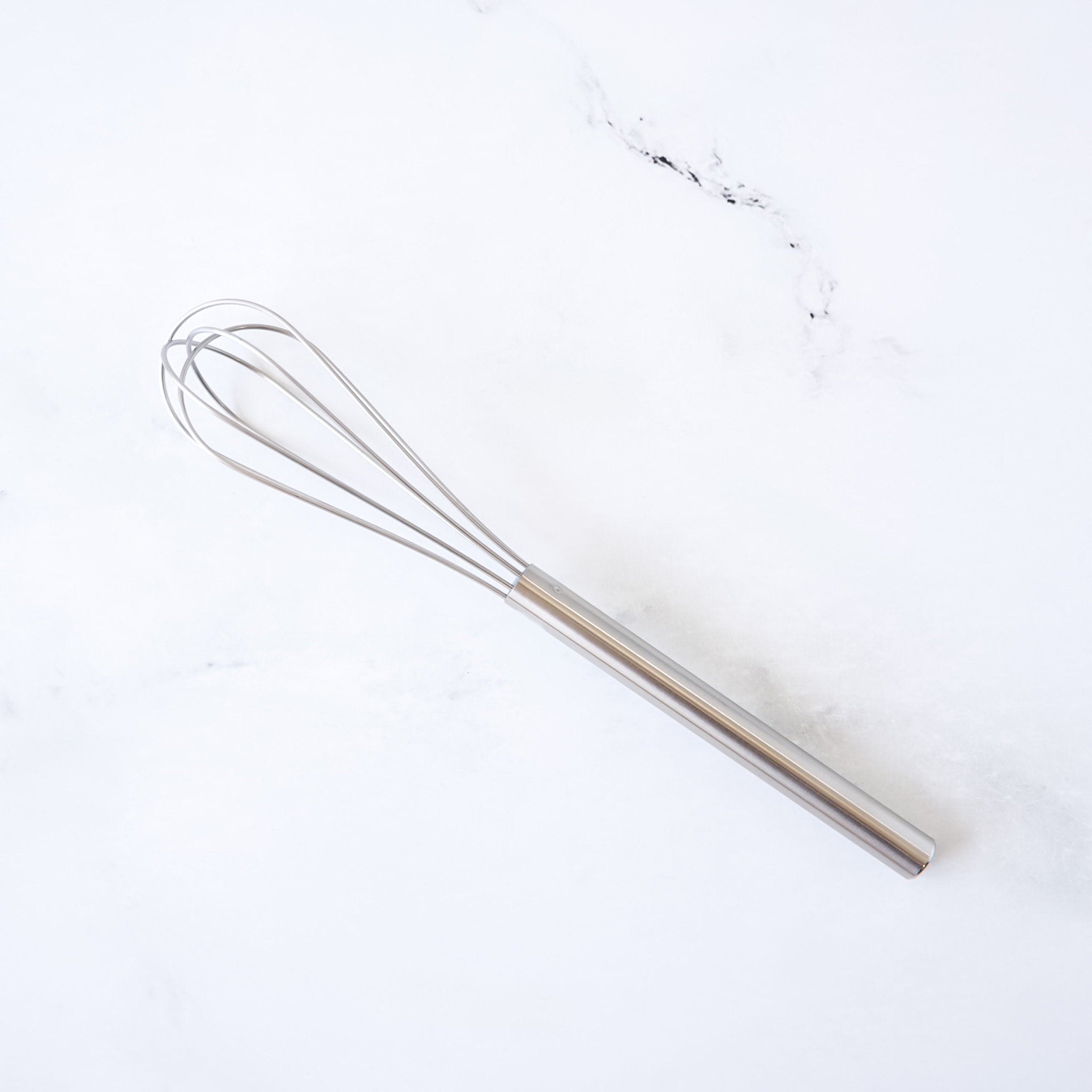 Stainless steel mini whisk on a white background
