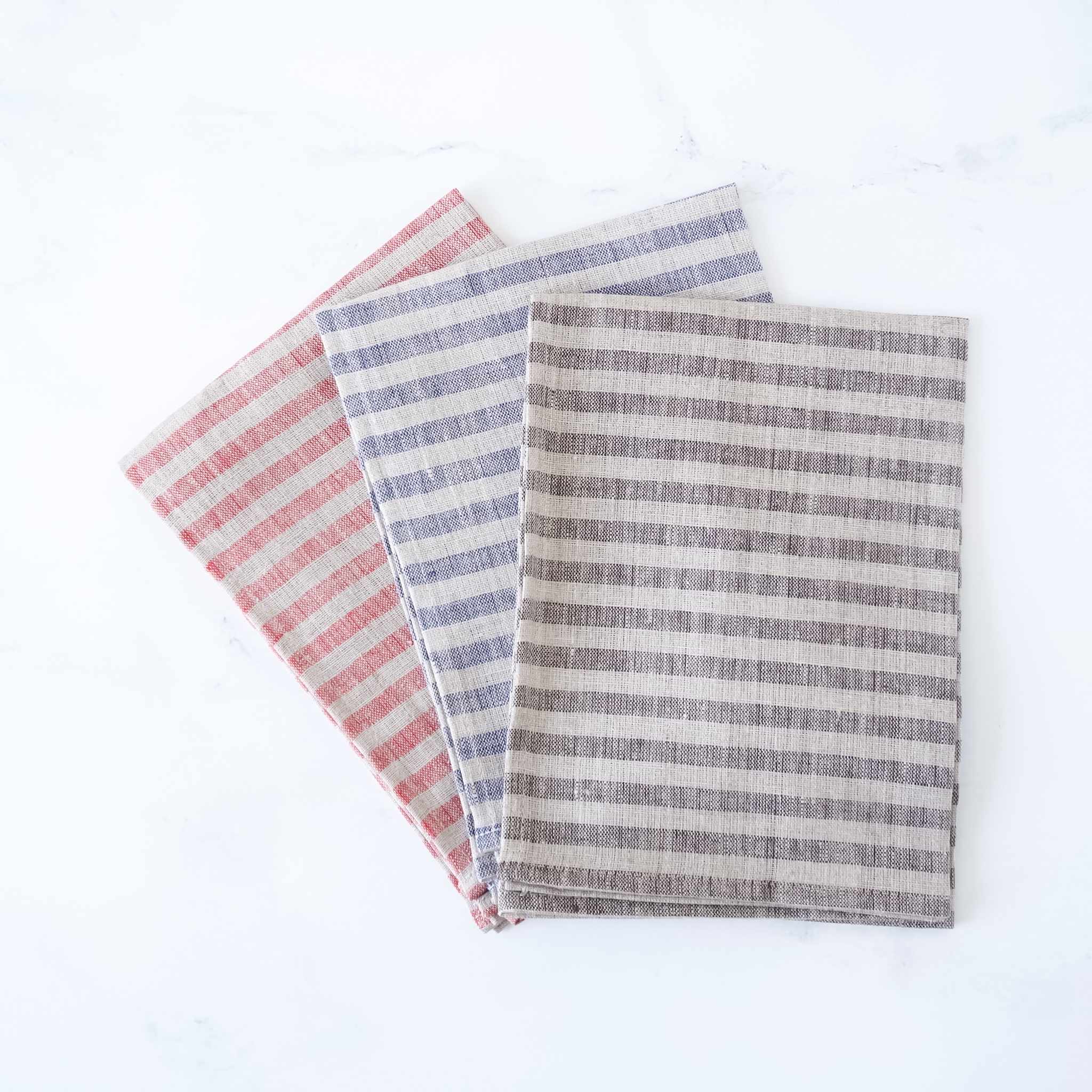 Three striped kitchen towels in red, blue, and gray on a white background