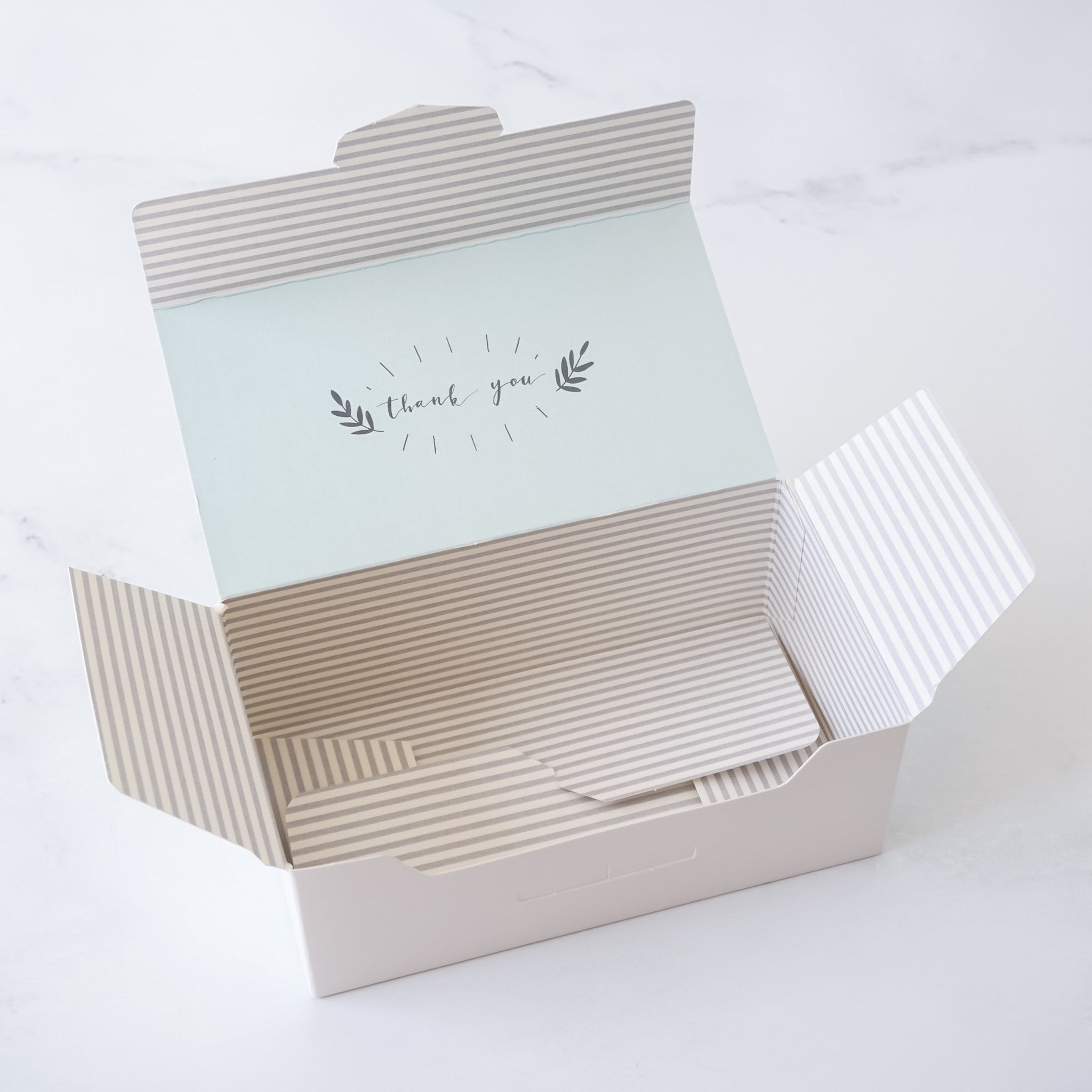 Open gift box with light gray striped pattern inside on a white background