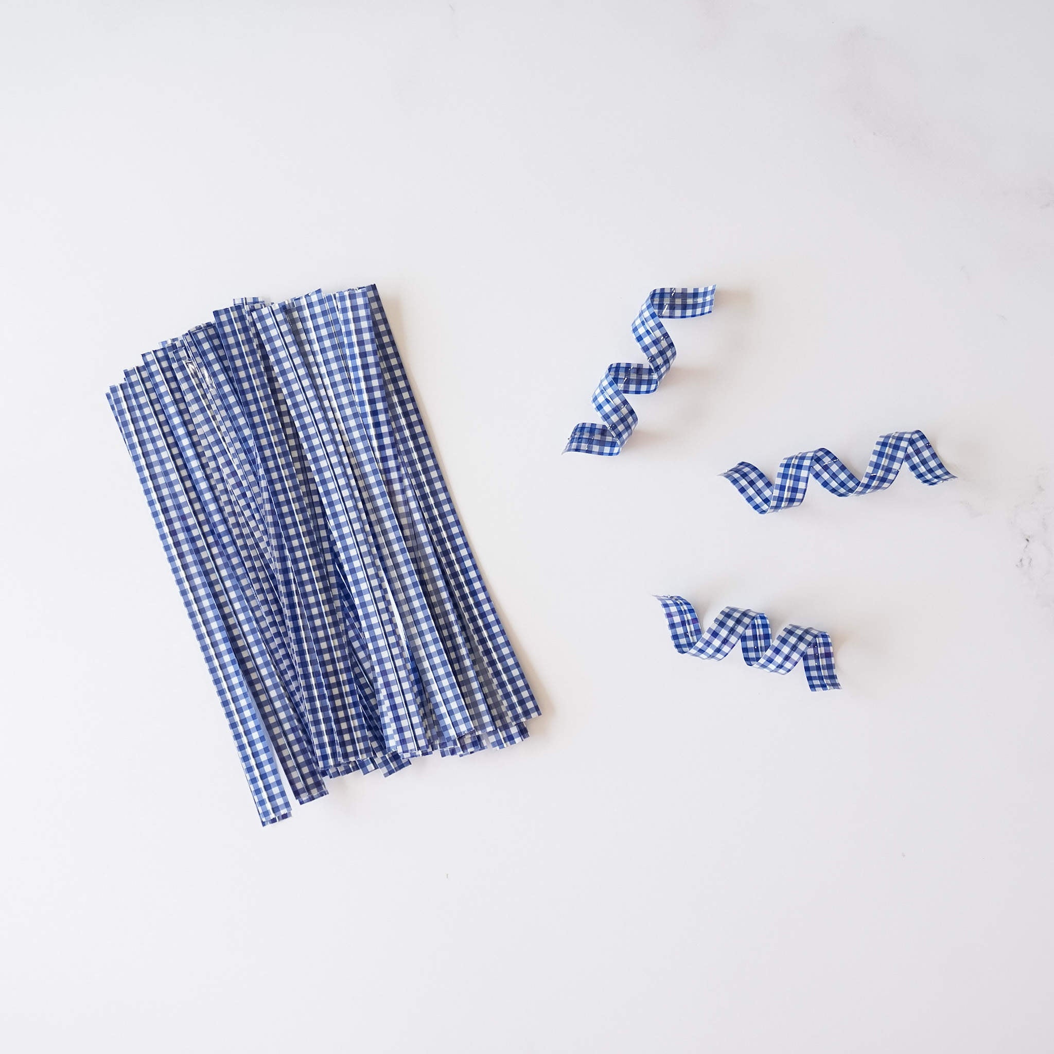 Blue gingham check twist ties arranged on a white surface.