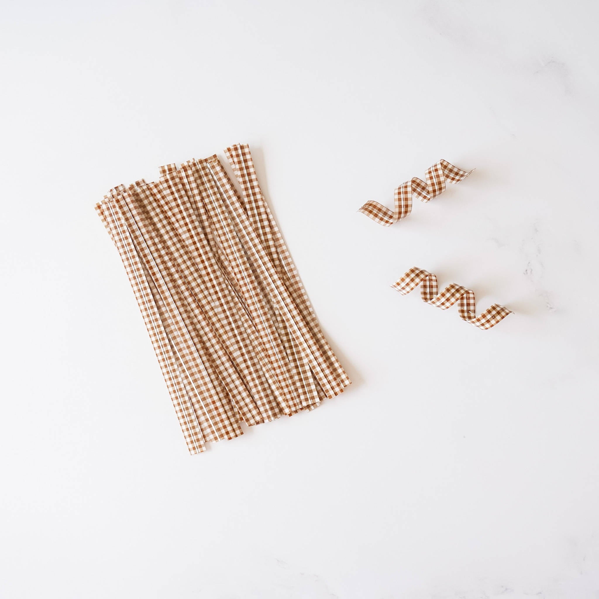 Brown gingham check twist ties arranged on a white surface.